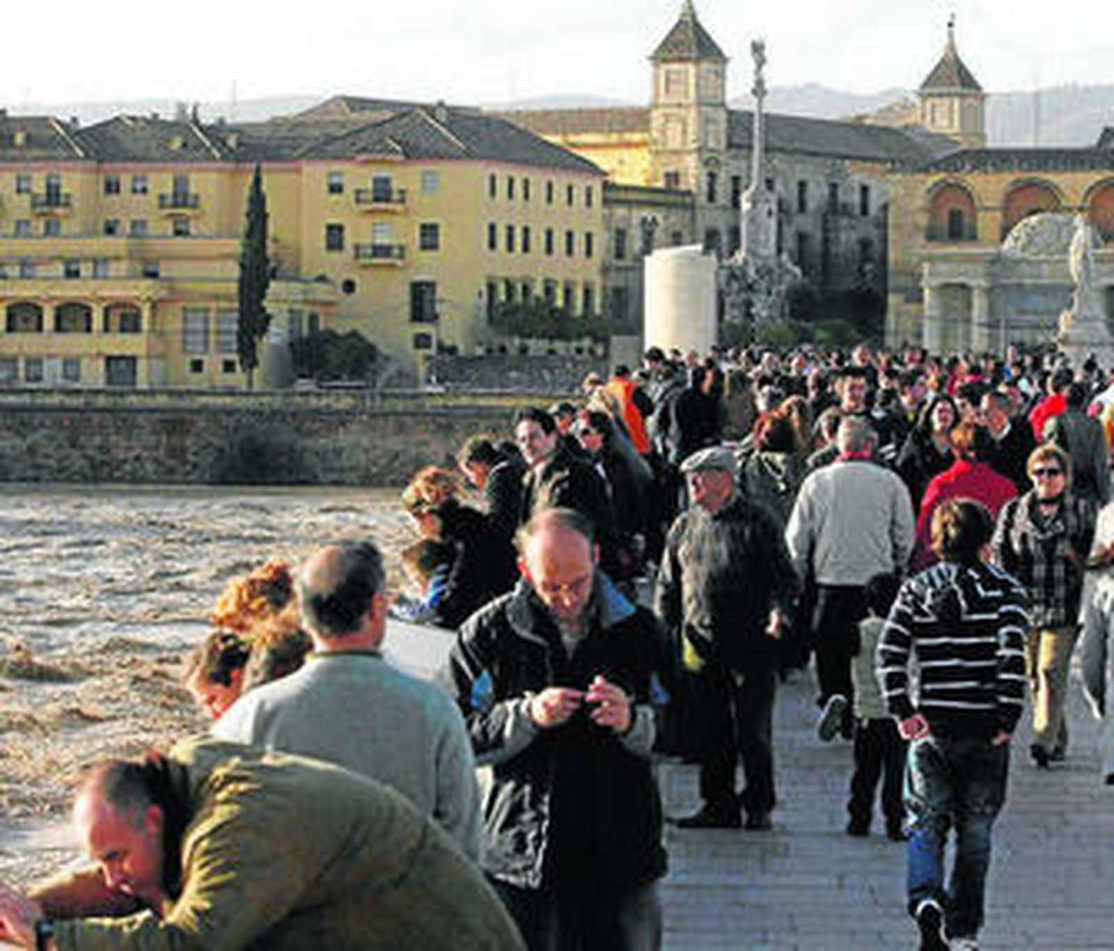 El Puente Romano, lleno de personas para ver y hacer fotos de la crecida del río Guadalquivir.