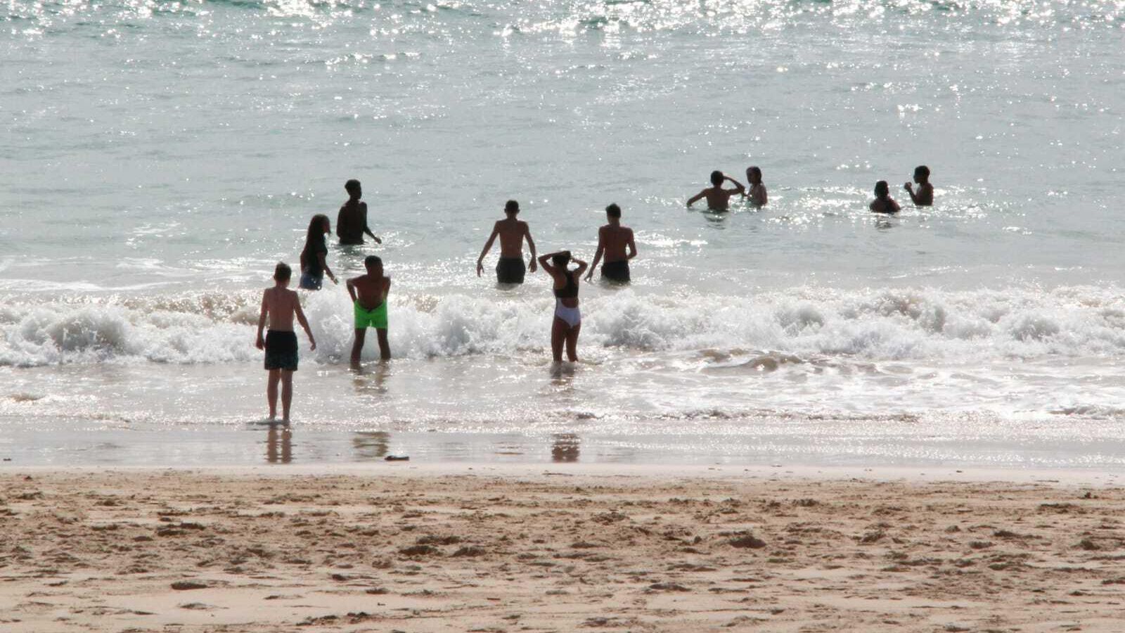 Un grupo de jóvenes bañándose este mediodía en La Barrosa