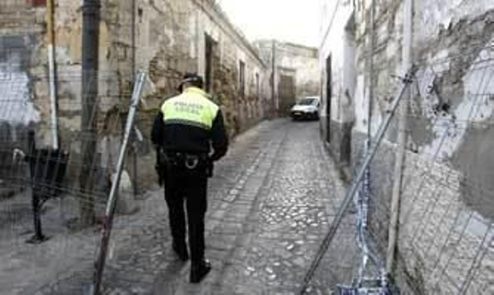 Un policía local, ayer, junto a las vallas que se estaban instalando para cerrar el paso por la calle Cabezas. /Pascual
