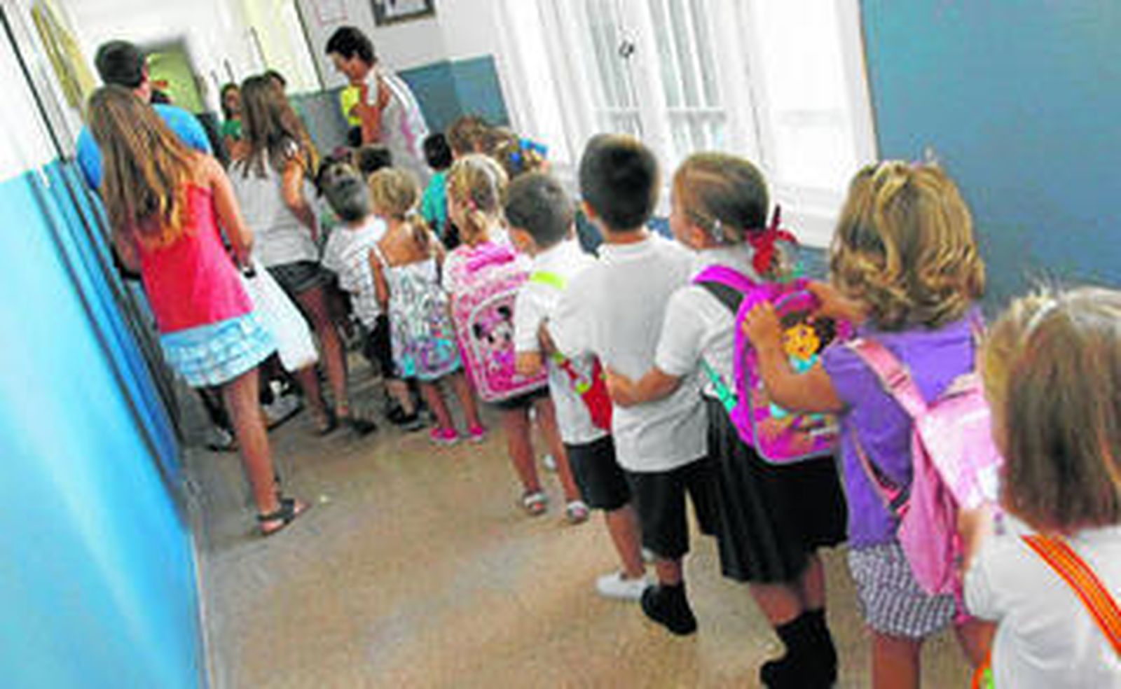 Un grupo de escolares entrando en fila en un aula de un centro educativo.