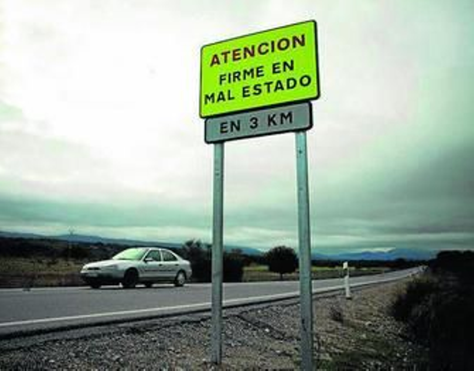 Un cartel informe del mal estado de una carretera de la Serranía.