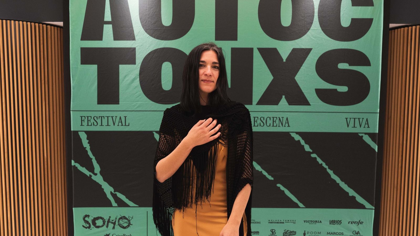 Alessandra García, directora de Autóctonxs, posando junto al cartel de la pasada edición.