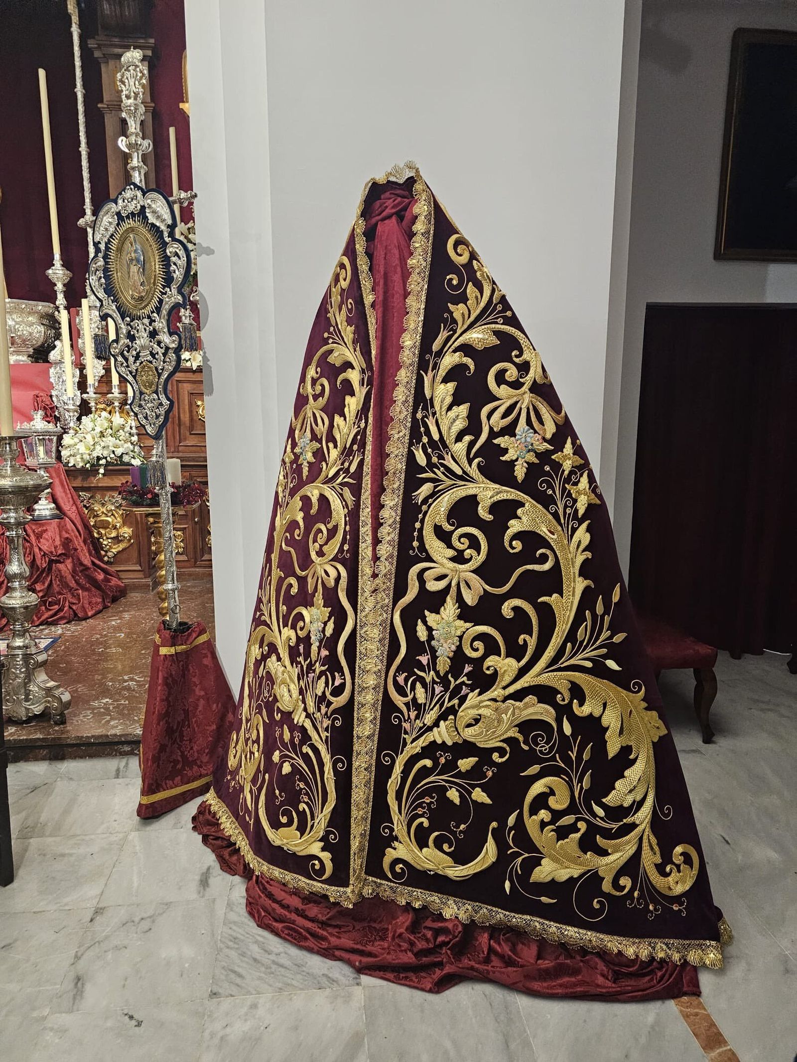 El manto ha sido bordado sobre terciopelo granate