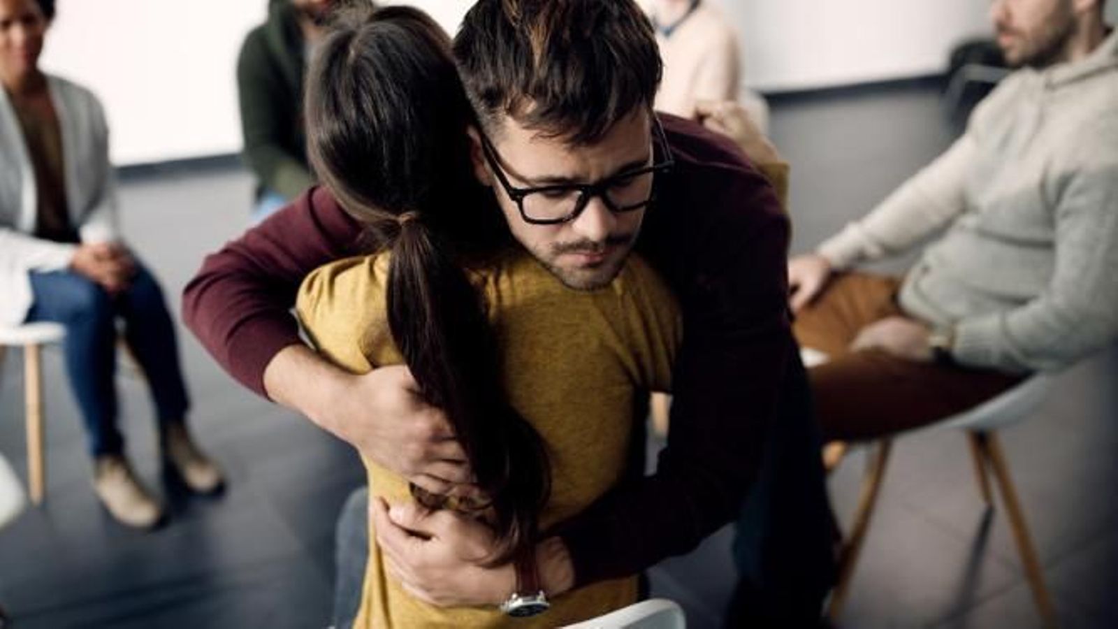 Dos integrantes de una terapia de grupo dándose un abrazo.