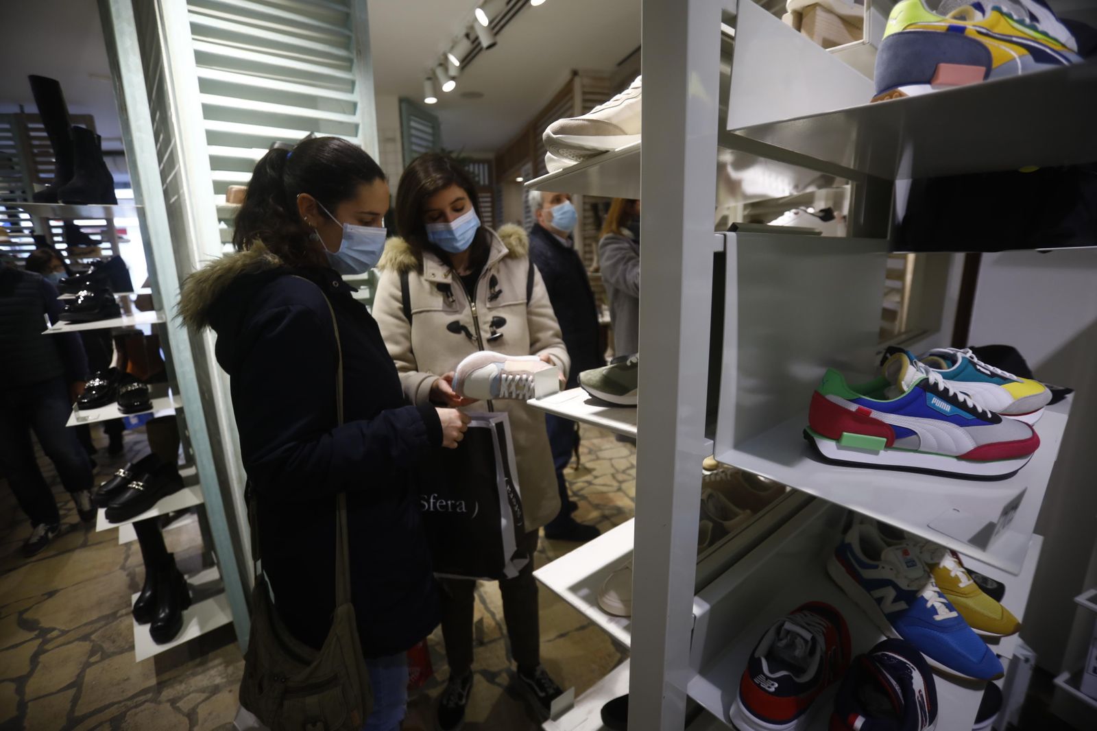 Dos mujeres miran zapatillas en una tienda.