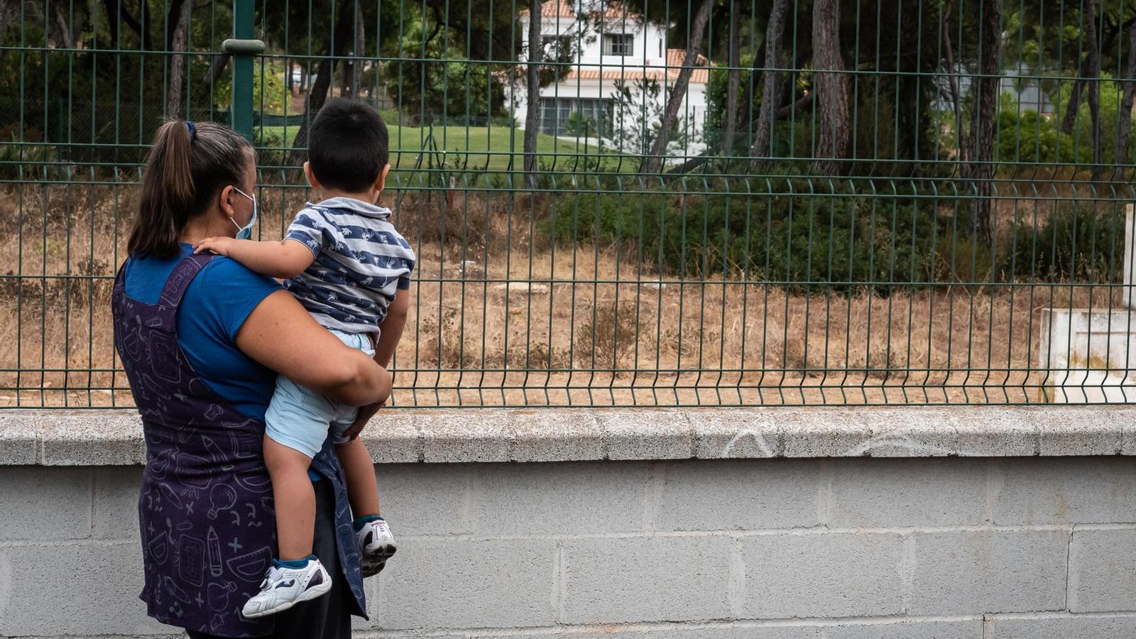 La educadora Inés sostiene a un pequeño en el patio de la escuela infantil.
