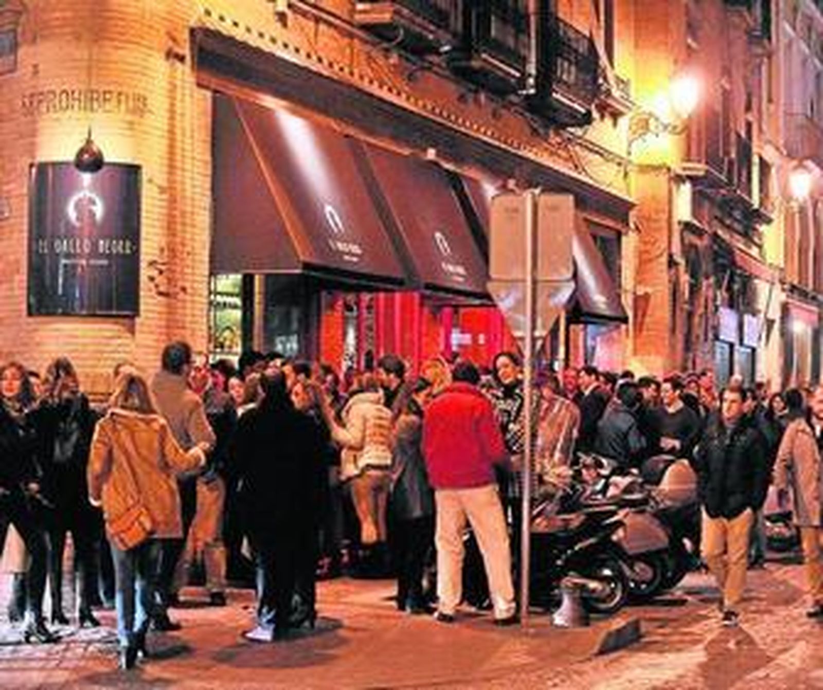 Un grupo de personas disfrutan de sus bebidas a las puertas de un bar de la calle Arfe.