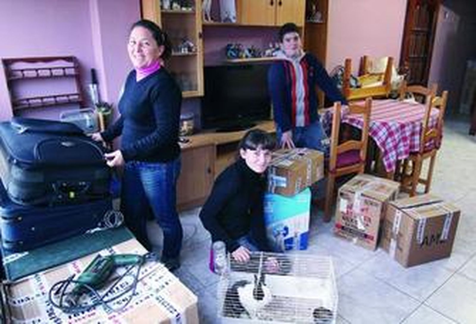 Chari y sus dos hijos, junto a varias de las cajas en las que aún guardan objetos de su antigua casa.