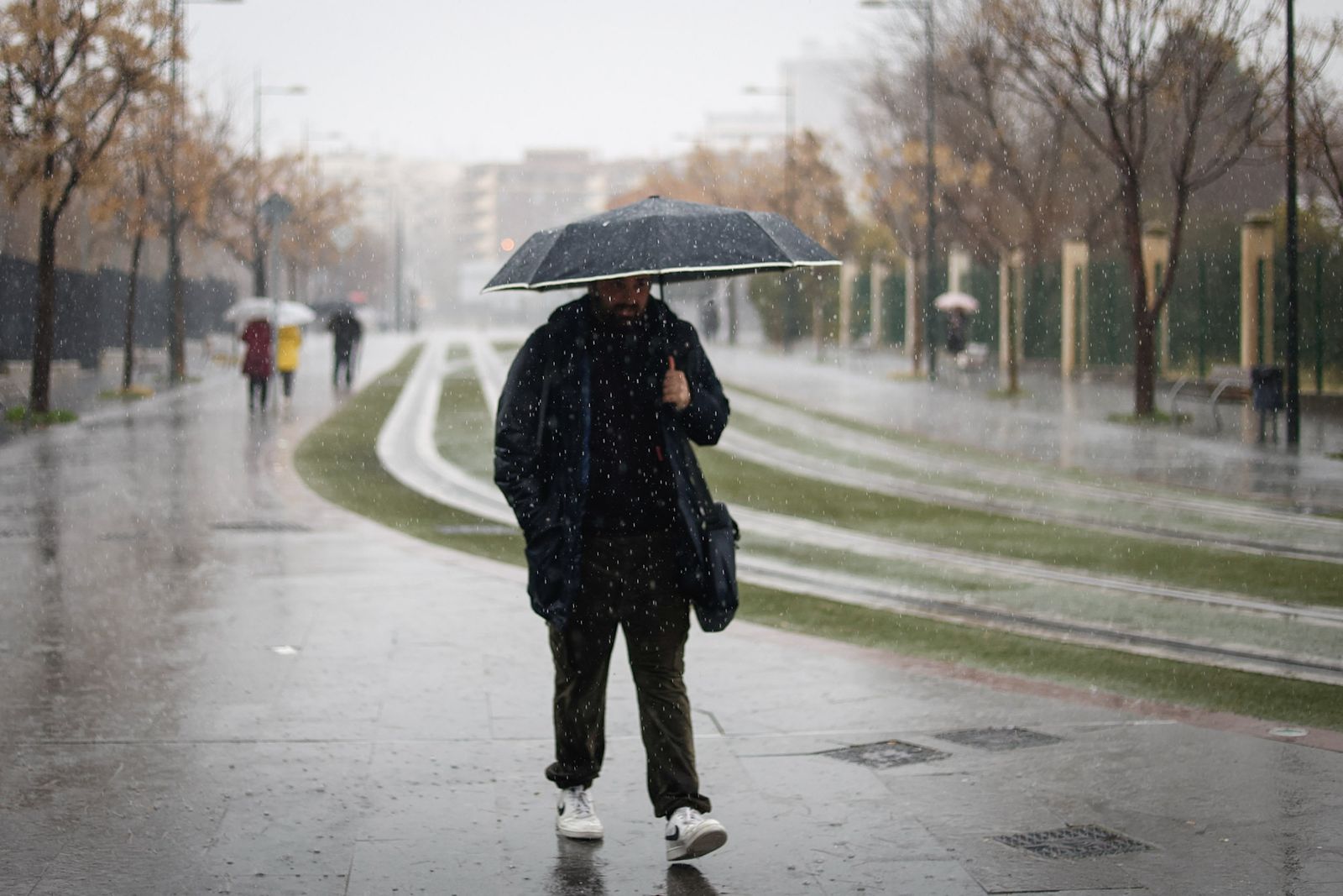 Una persona se protege de la lluvia en Granada con un paraguas.