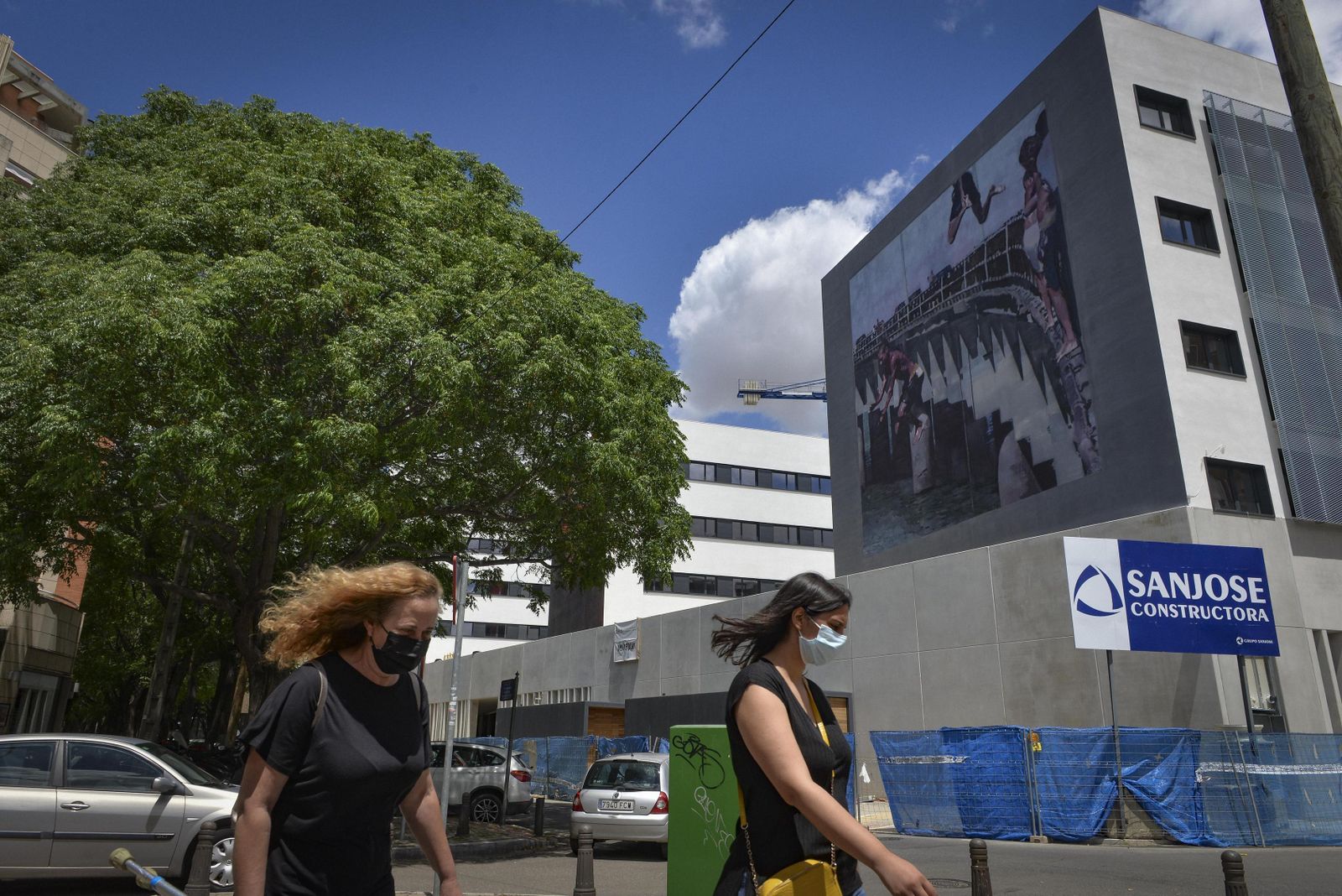 Dos paseantes junto al edificio con el mural de la residencia de estudiantes.