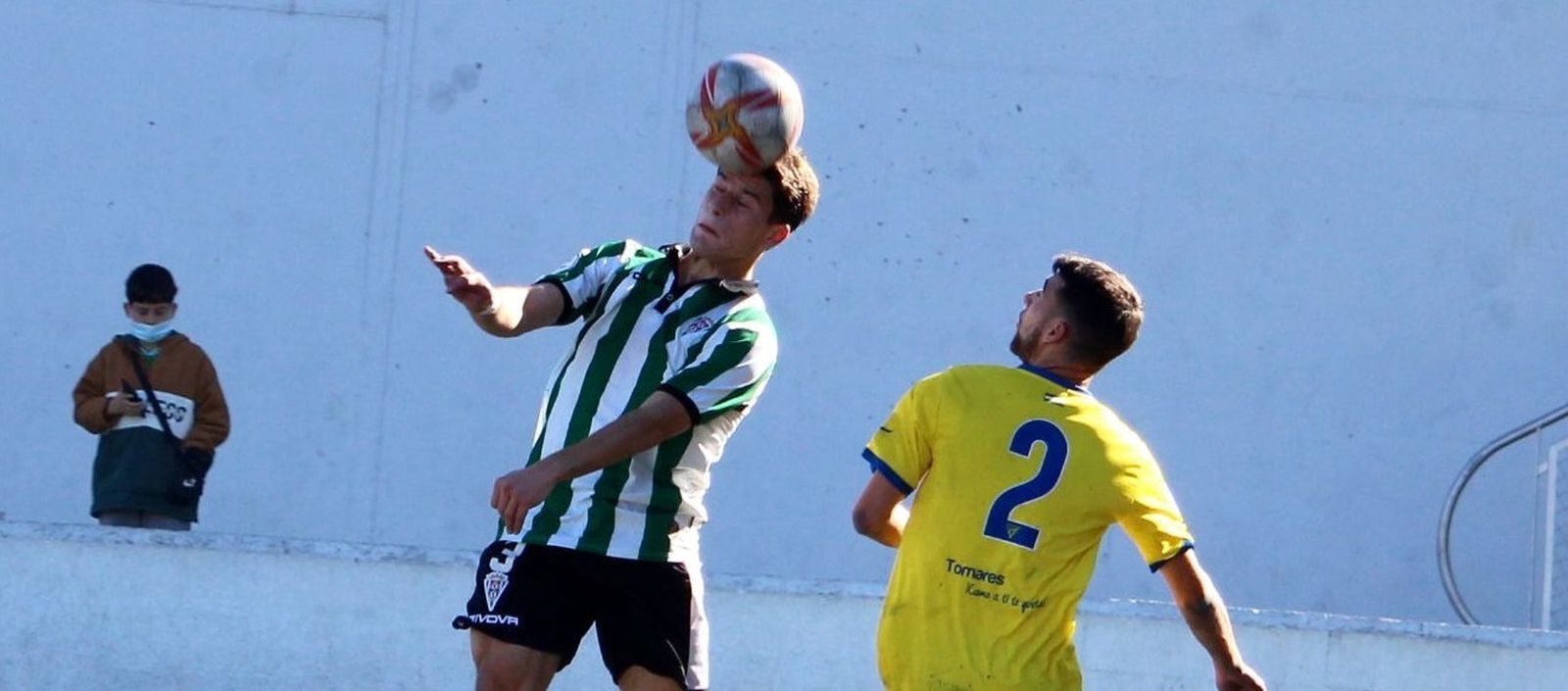 Manolillo cabecea el balón ante la presencia de Juan Delgado.