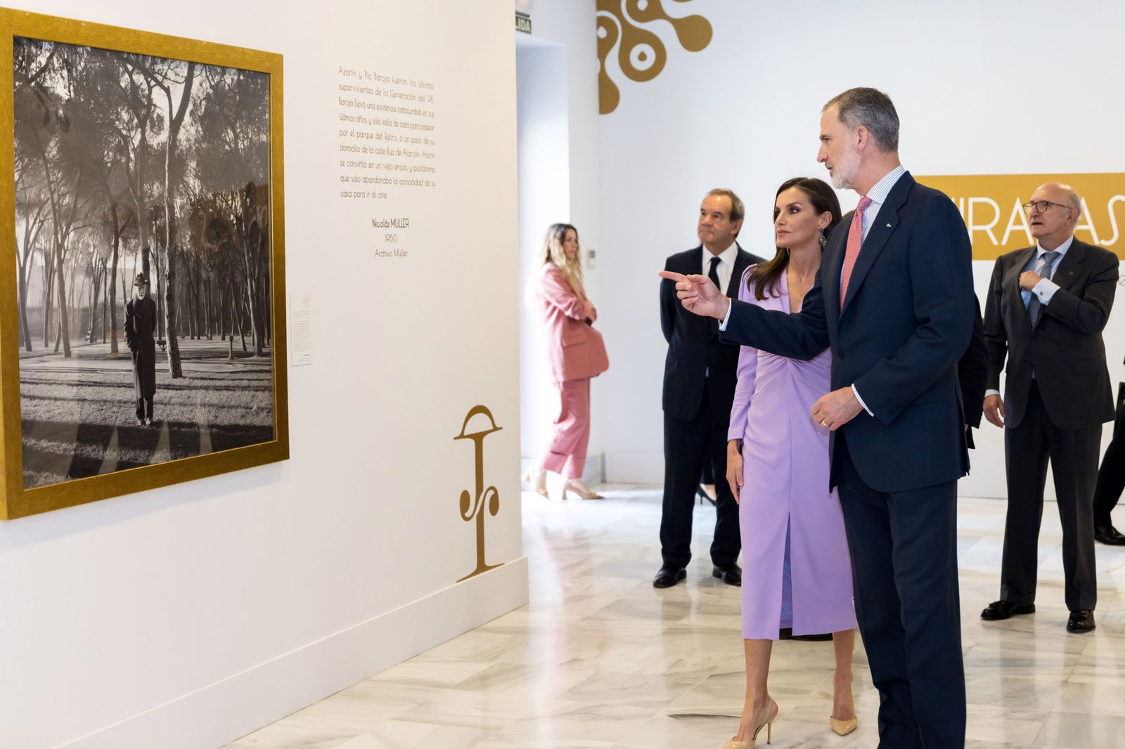 Los Reyes de España ante el retrato de Pío Baroja paseando por el Retiro de la exposición con fotografías de la RAE.