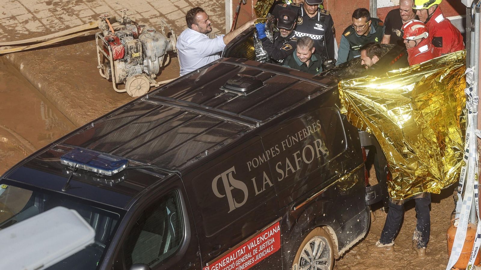 Guardias civiles y bomberos trasladan el cuerpo sin vida de una víctima a un furgón de una funeraria en La Torre de Valencia.
