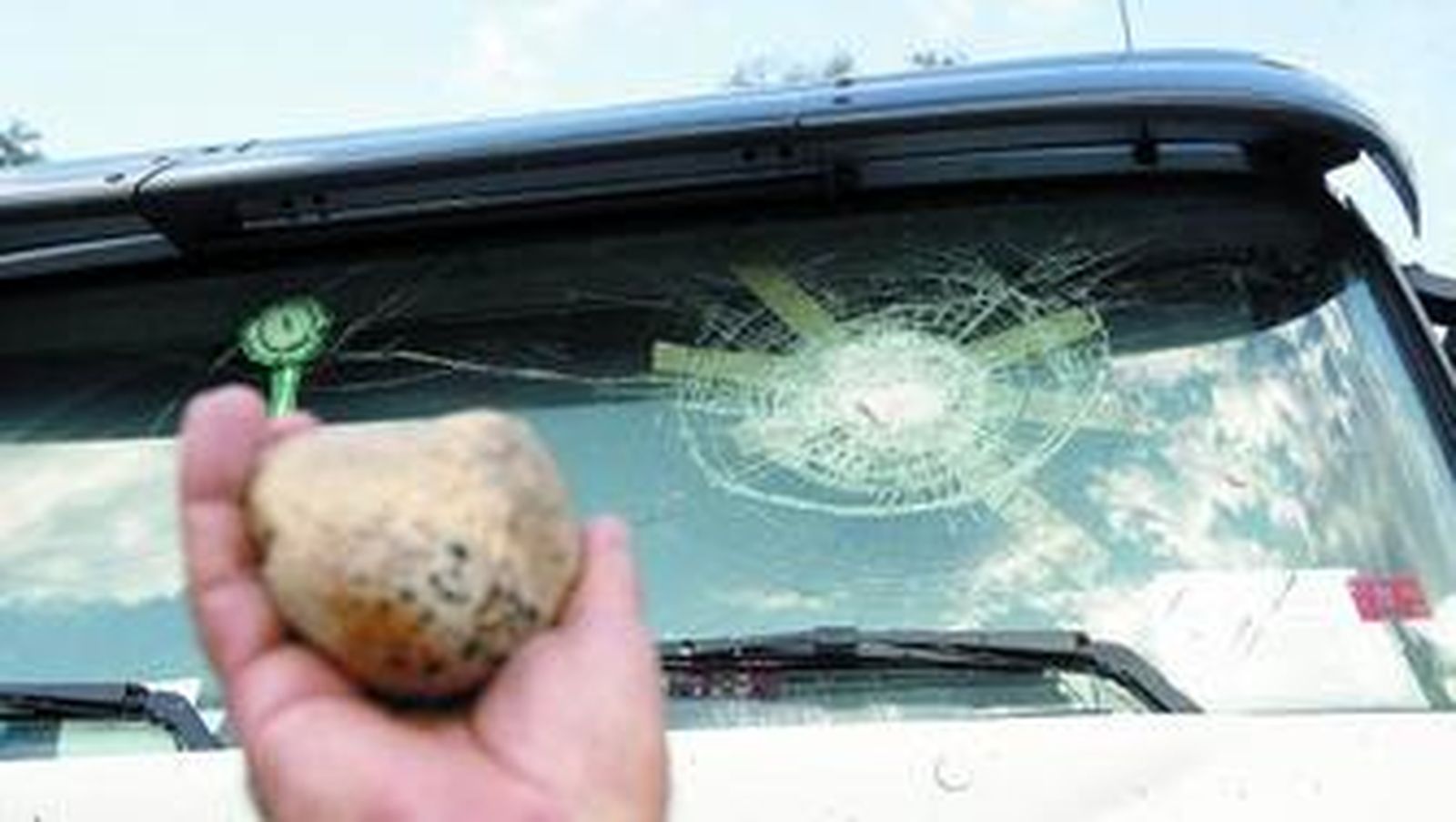 Unos de los transportistas muestra una de las piedras que le lanzaron y que rompió la luna.