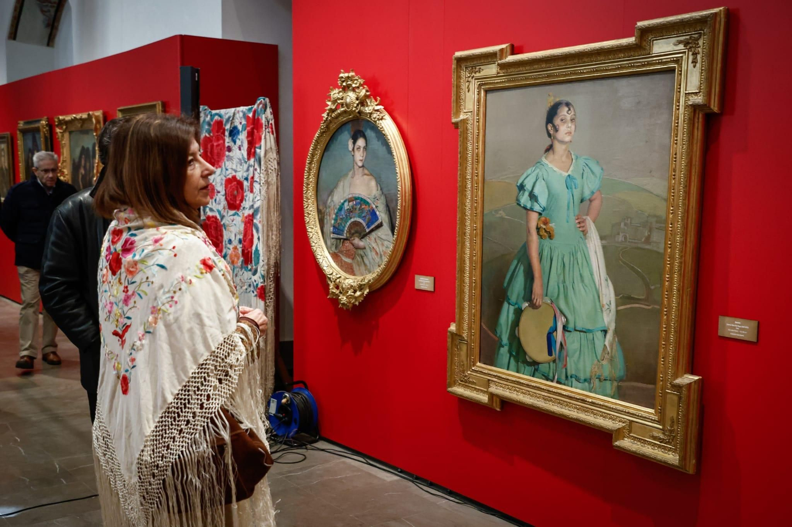Una mujer observa varios de los cuadros expuestos.