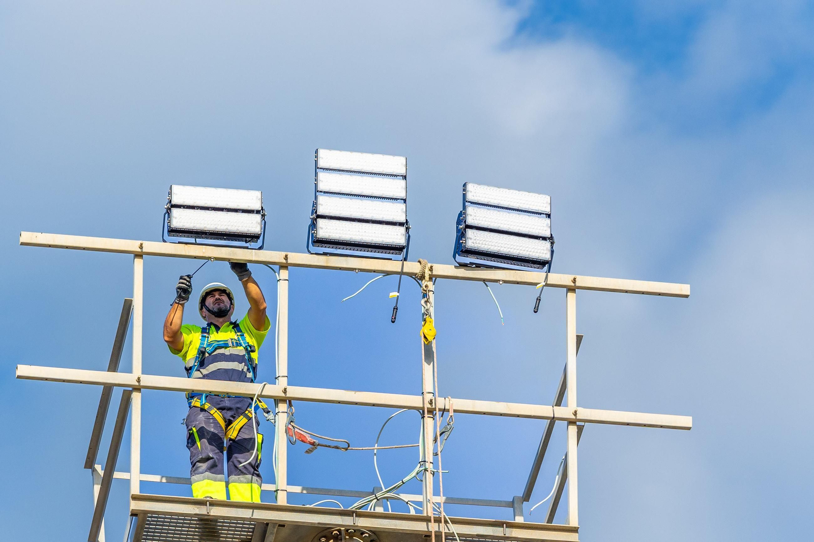 Un operario trabaja en la sustitución de la iluminación del campo de hockey en San Fernando