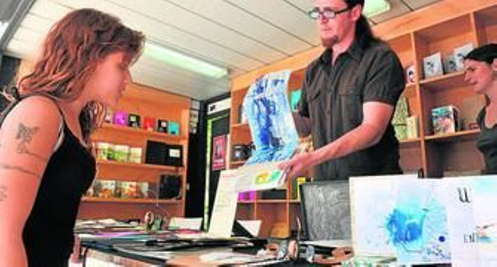 Sobre estas líneas, Antonio García Villarán muestra a una visitante uno de los libros de artista que ofrece en la caseta de su editorial, Cangrego Pistolero. A la derecha, desplegando otro de los ejemplares de la colección.