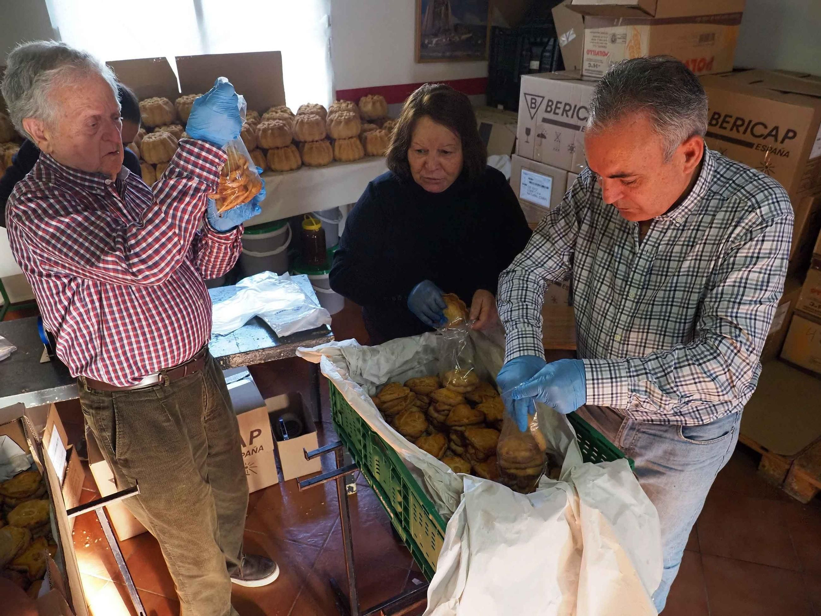 Miembros de las familias Borrego Martín y Ramos Díaz, una de las mayordomías de este año, envasan tortas para su posterior reparto entre los vecinos de Puebla de Guzmán