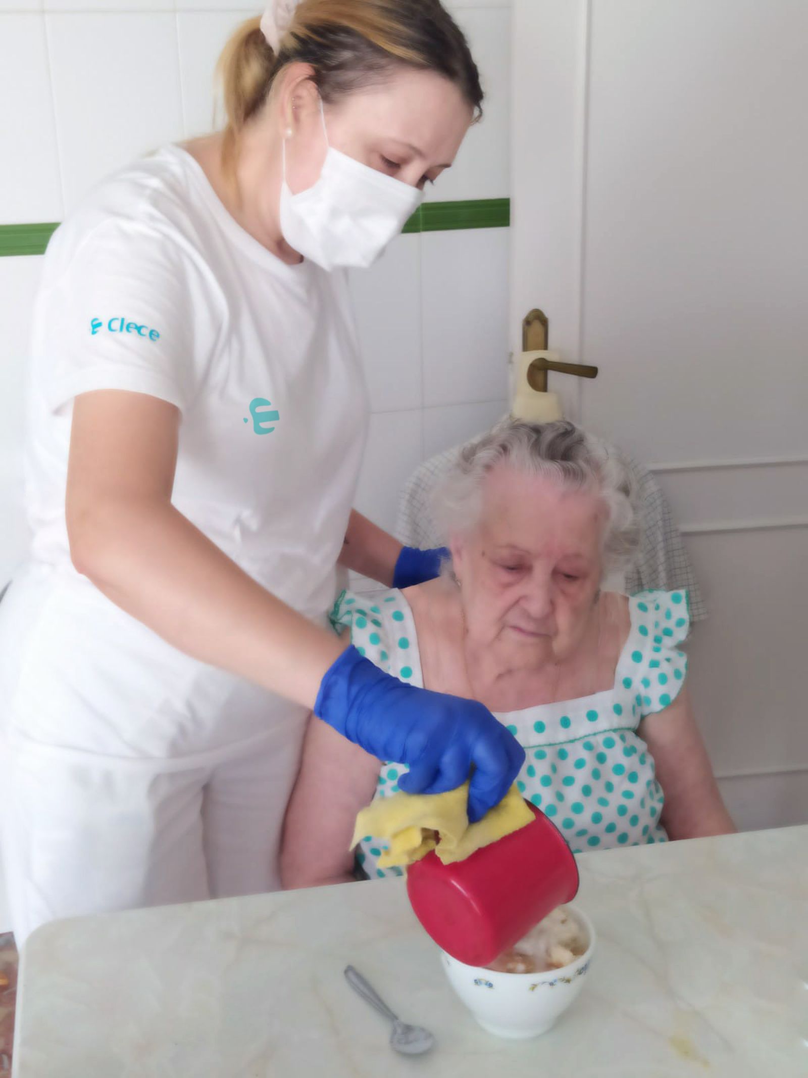 Una asistente de ayuda a domicilio ayuda a desayunar a una usuaria.
