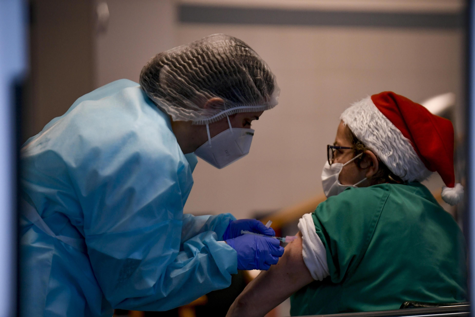 Una trabajadora de La Milagrosa de Armilla recibe la vacuna con un gorro de Santa Claus