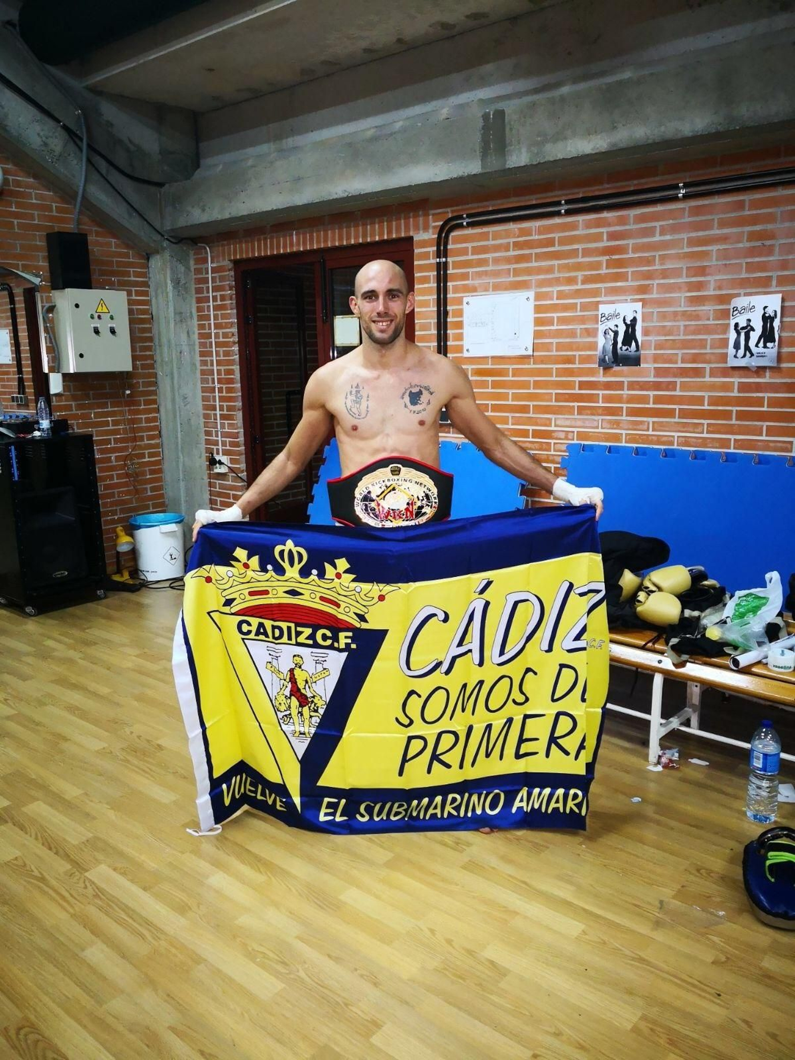 Carlos Coello posa tras el combate con el cinturón de campeón mundial y una bandera del Cádiz