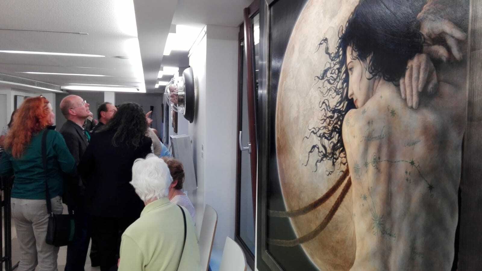 En primer plano, una de las obras de la muestra, en la sala llena de público.