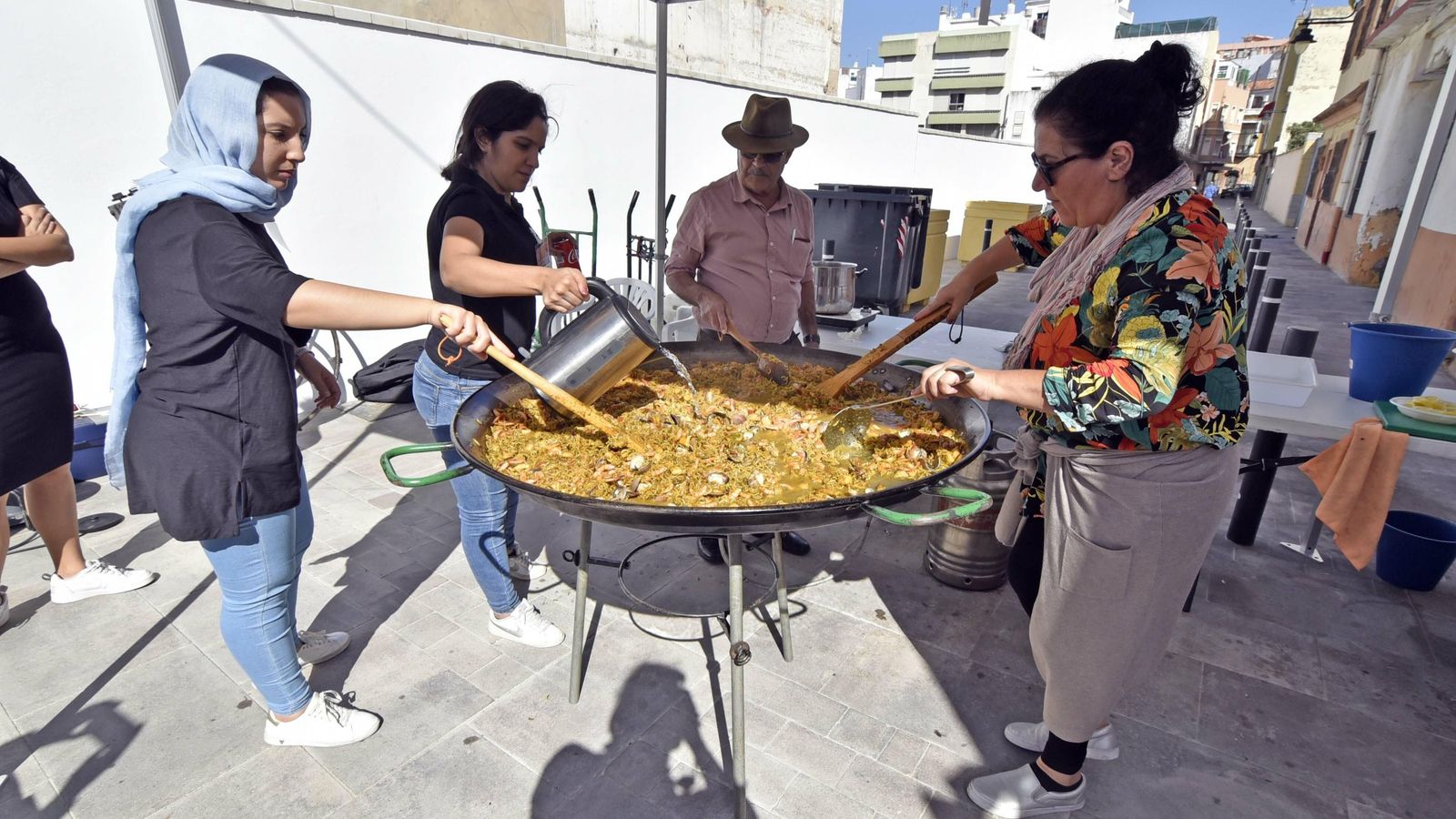 Varias personas elaboran la fideuá en la calle Cayetano del Toro de Algeciras.