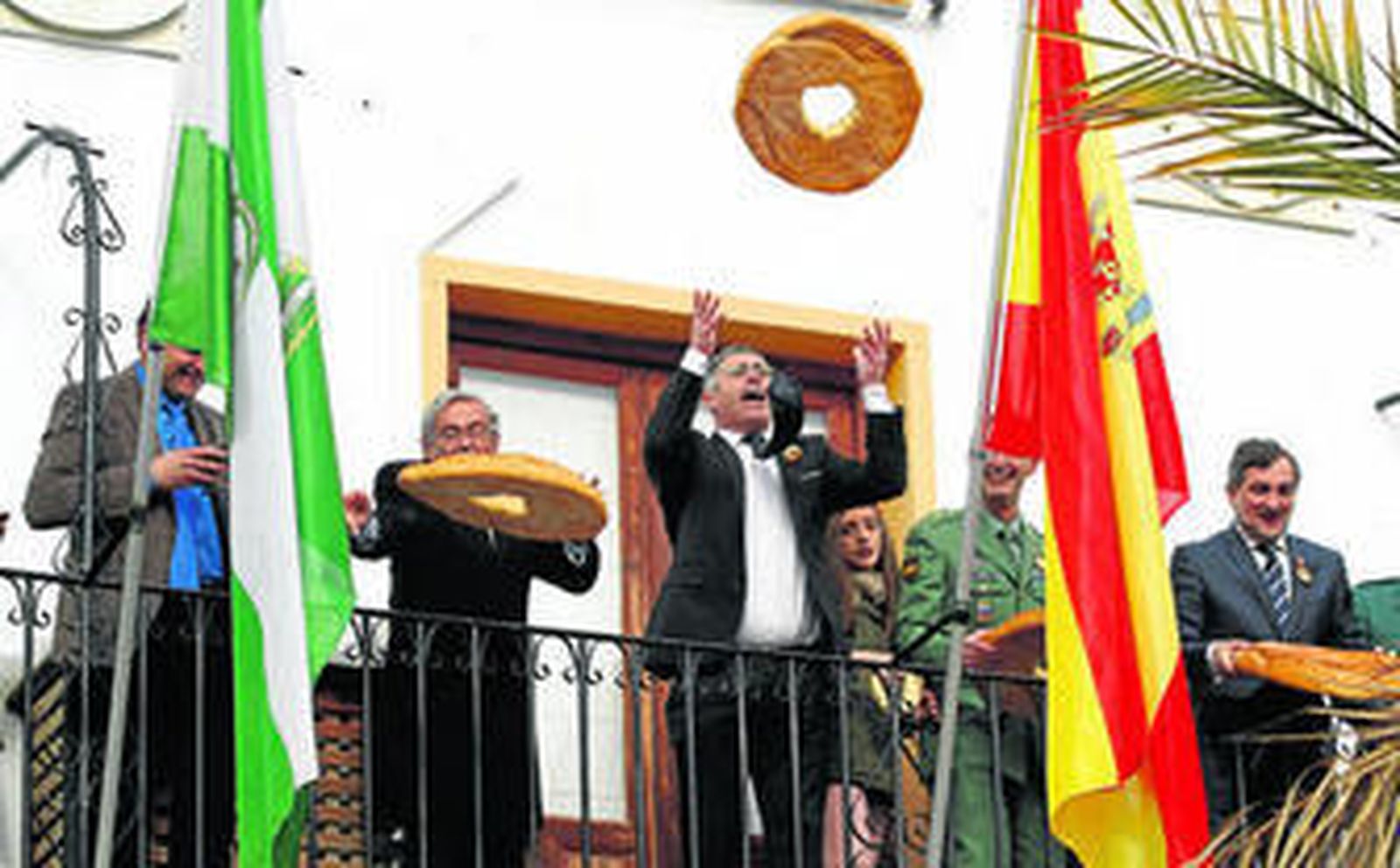 El alcalde de Olula, Antonio M. Pascual, lanza una gran rosca a los santos desde el balcón del Ayuntamiento, acompañado por el subdelegado del Gobierno y mandos militares.