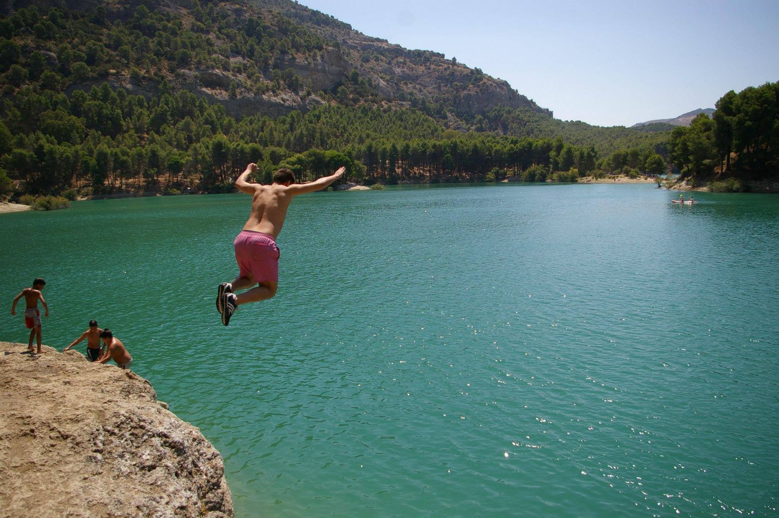 Un joven salta al agua de un pantano.