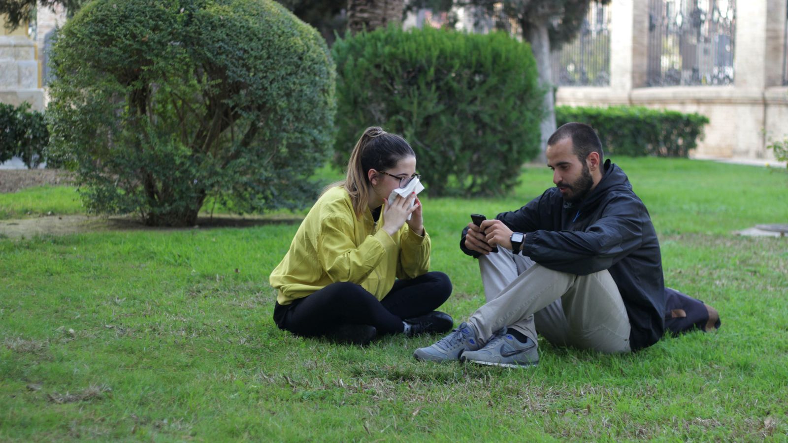 Dos jóvenes en una zona ajardinada.