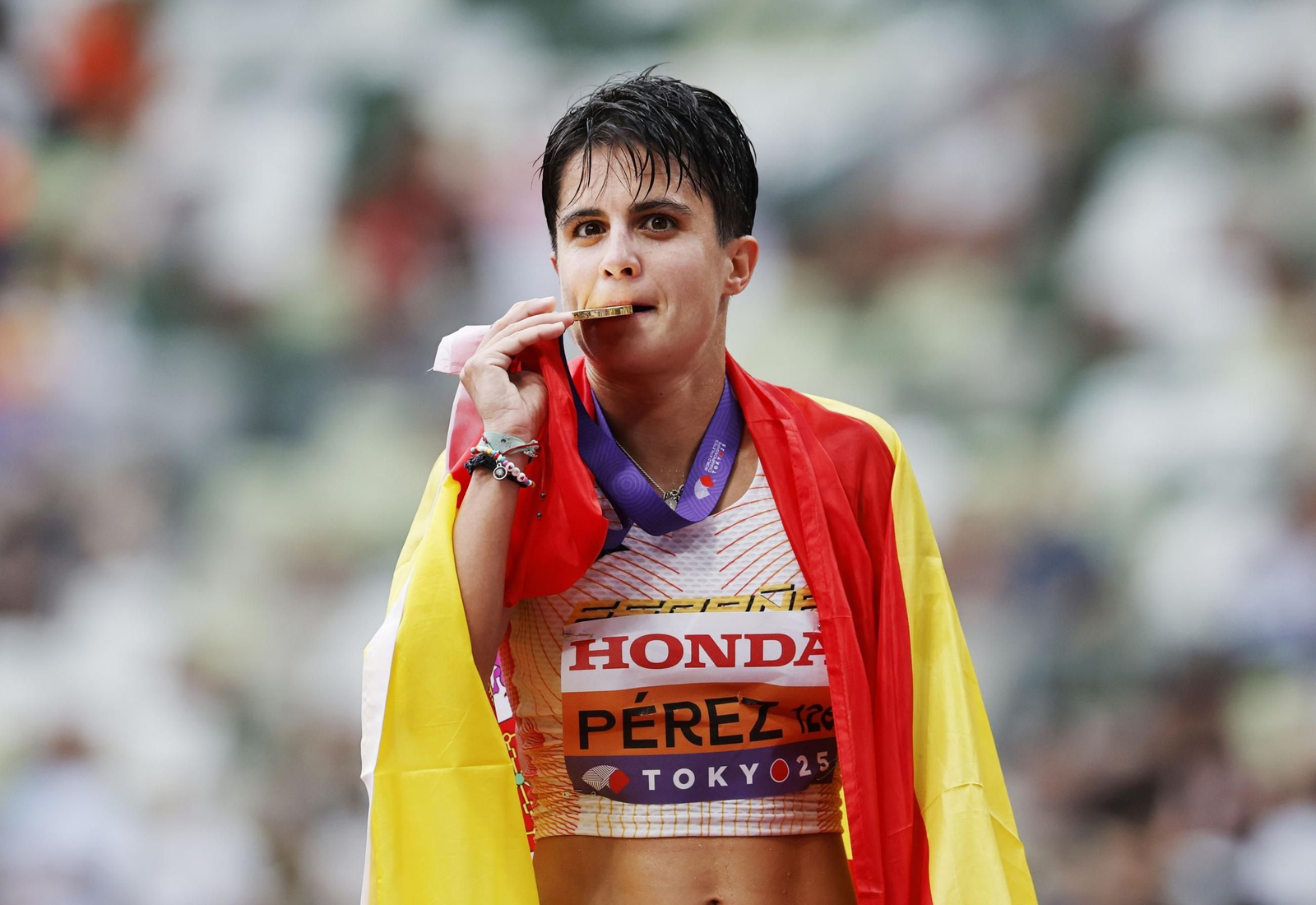 María Pérez, con la bandera de España, muerde su medalla de oro
