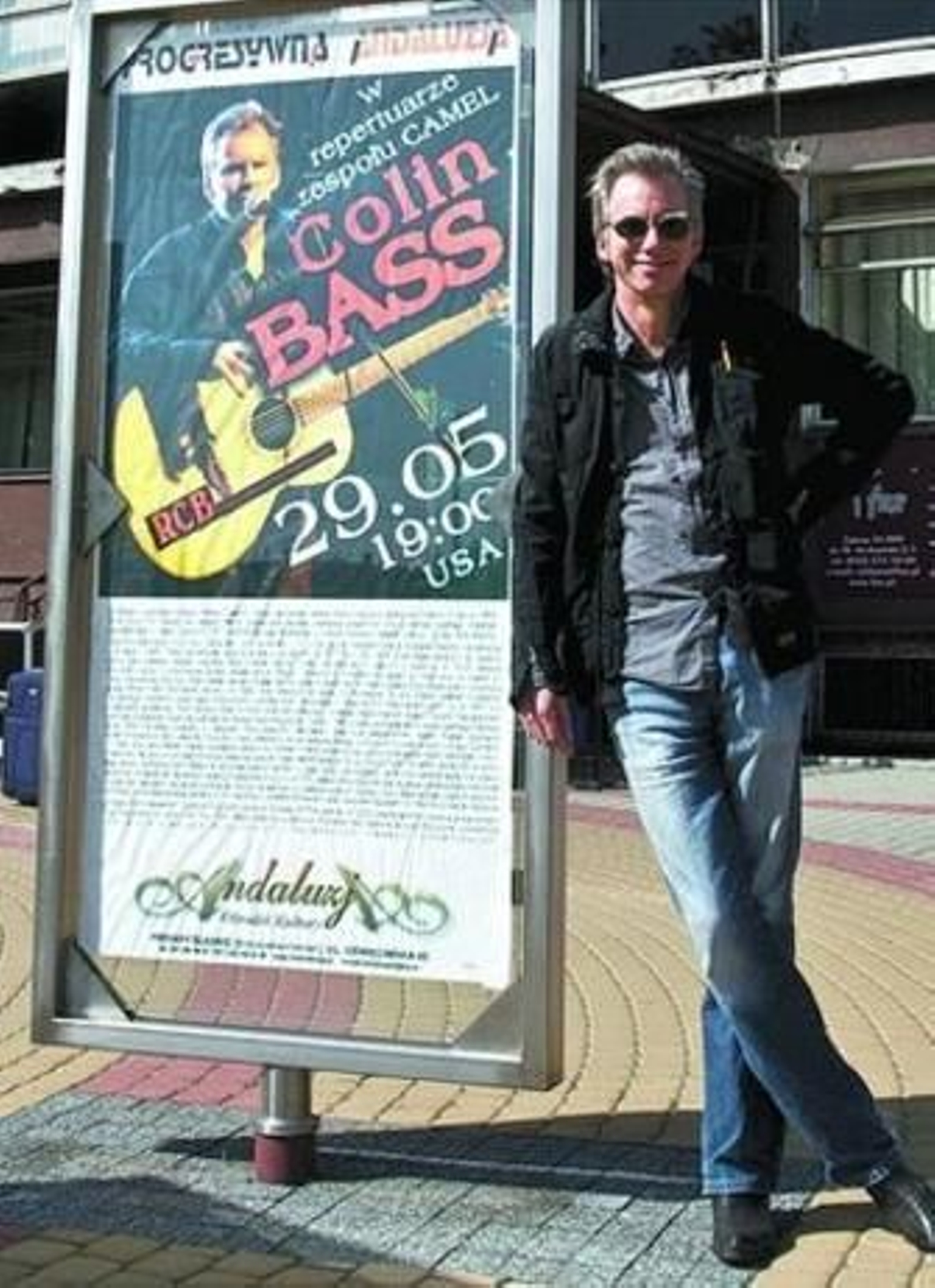 Colin Bass posa ante el cartel anunciador de uno de sus conciertos.