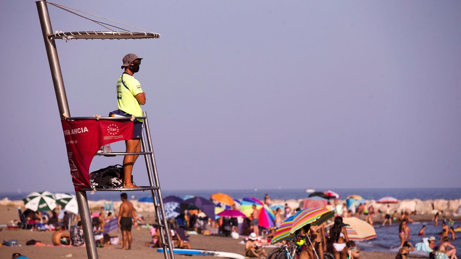 Un socorrista con mascarilla en la playa de la Malagueta