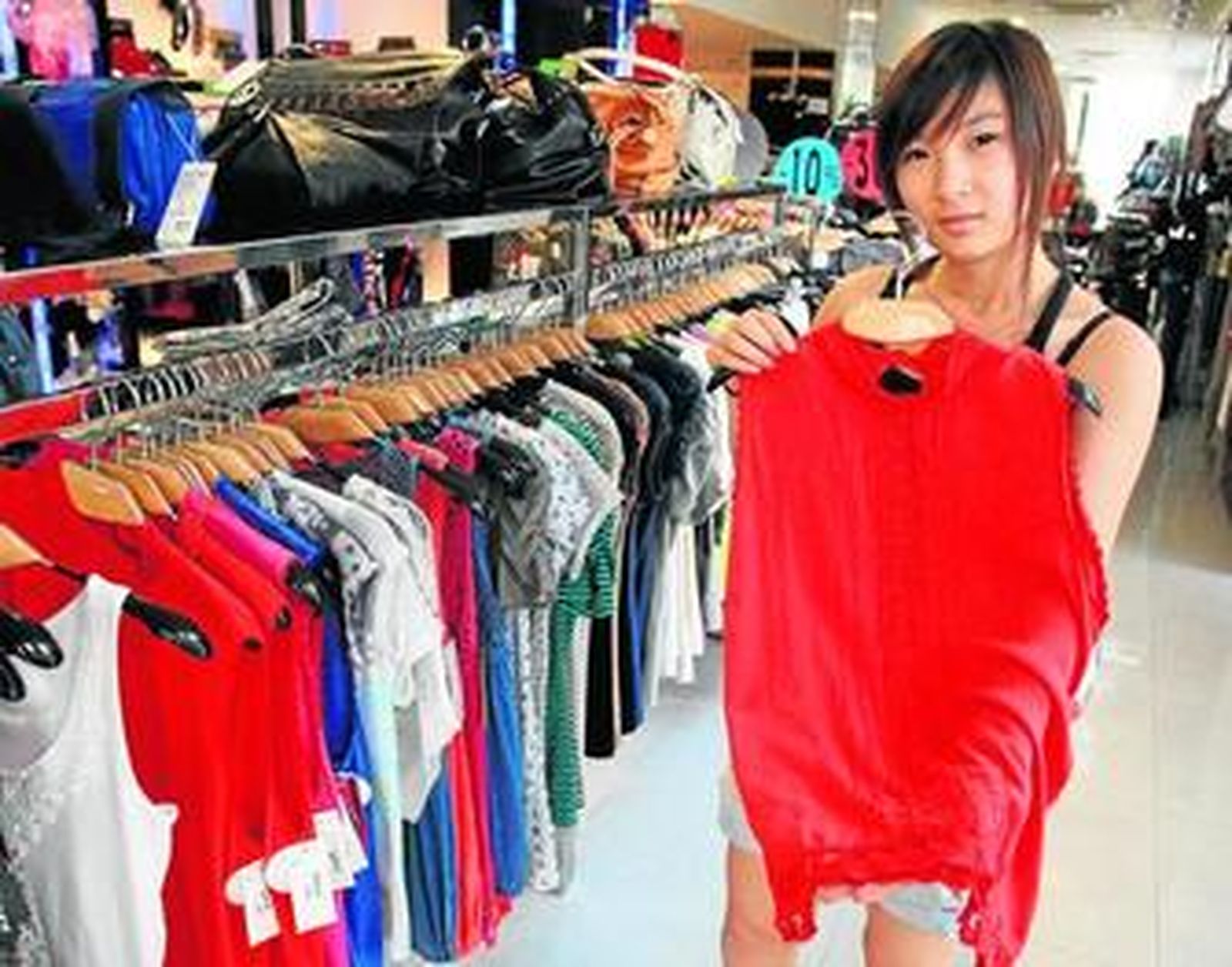 La dependienta de la tienda N&B muestra una de las blusas que se pueden comprar en este negocio.