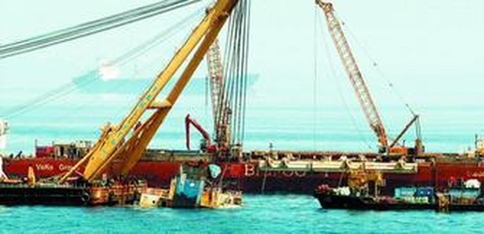 Las cadenas de la grúa flotante tiran del casco del chatarrero para elevarlo hasta el 'Bigfoot'.