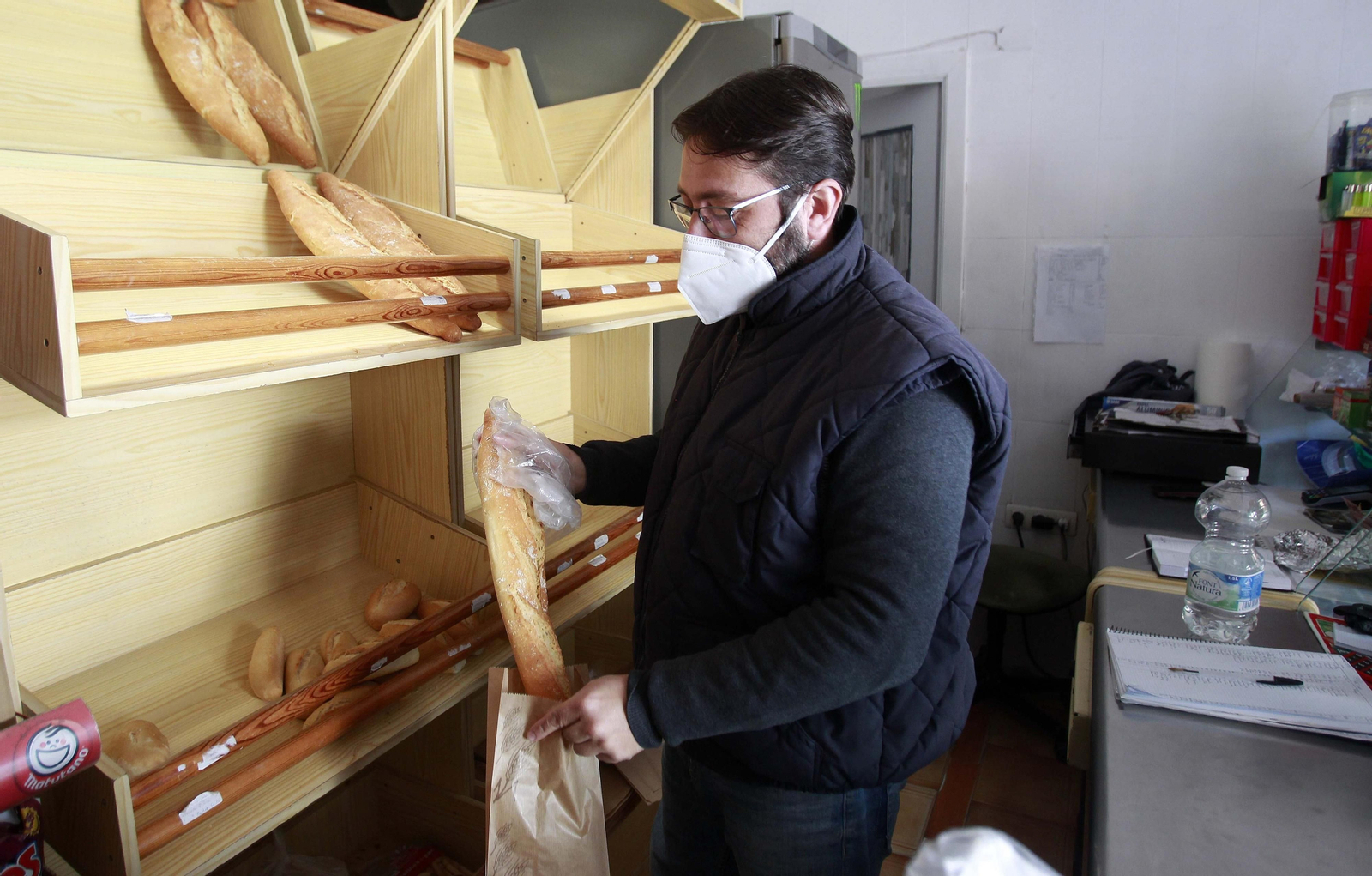 Un hombre despacha pan en Algeciras con una mascarilla FFP2.