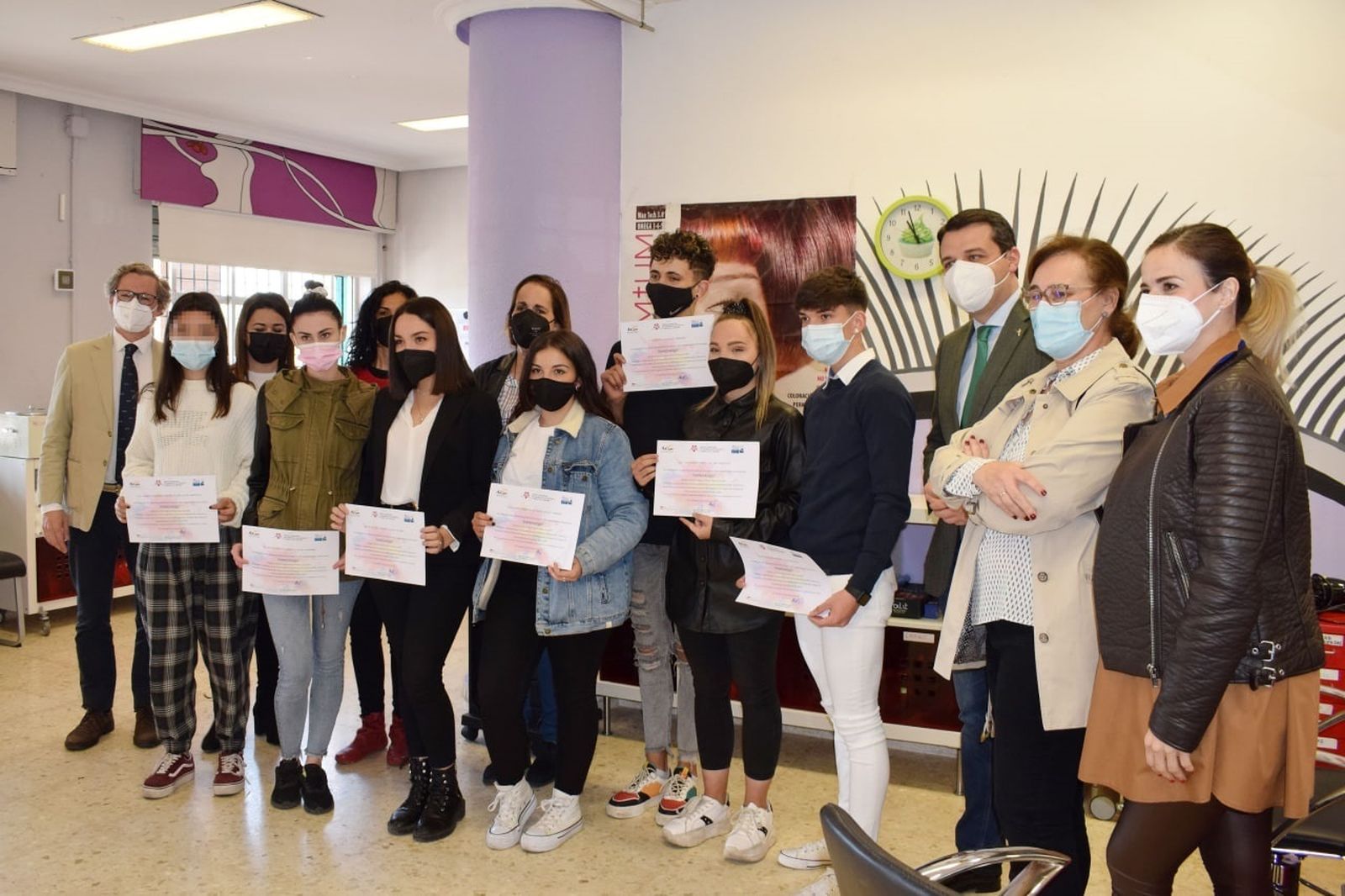 Ocho alumnos reinsertados laboralmente de Las Palmeras sostienen sus títulos de peluquería.