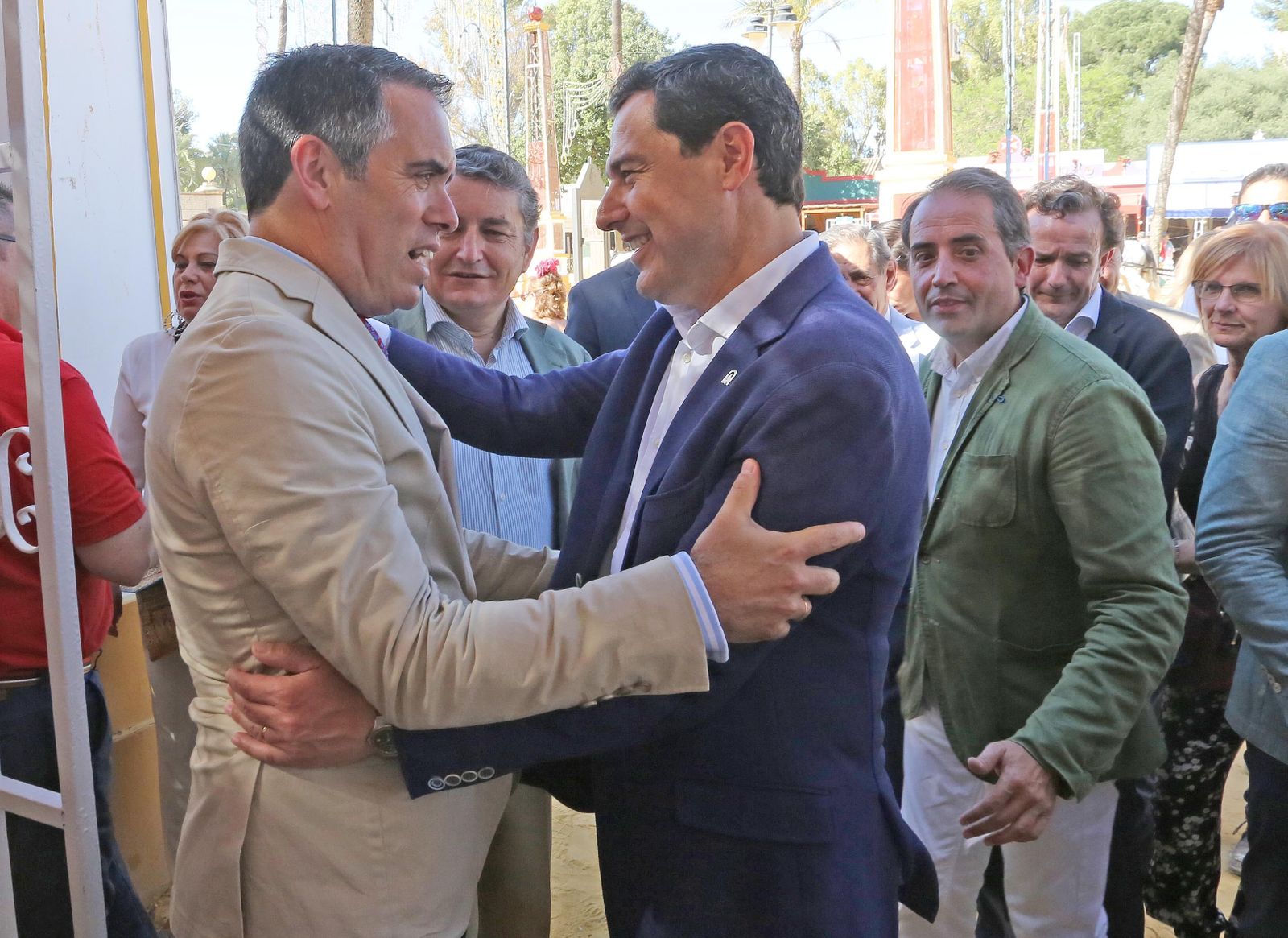 El presidente andaluz Juanma Moreno saluda a su llegada a la caseta al director de Diario de Jerez, Rafael Navas, en presencia de Antonio Sanz y Antonio Saldaña.