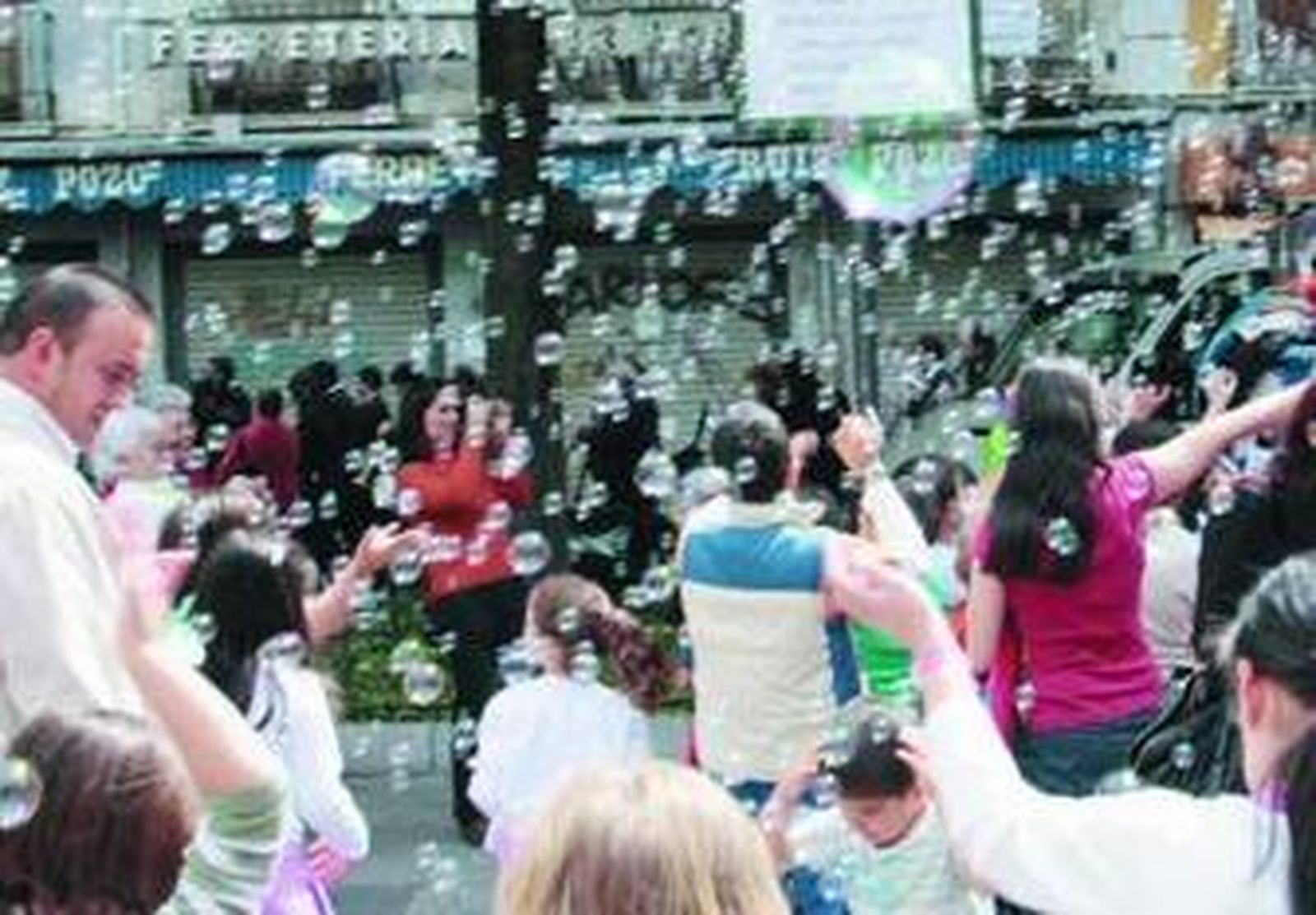 Un grupo de niños juega bajo un cielo de pompas de jabón.