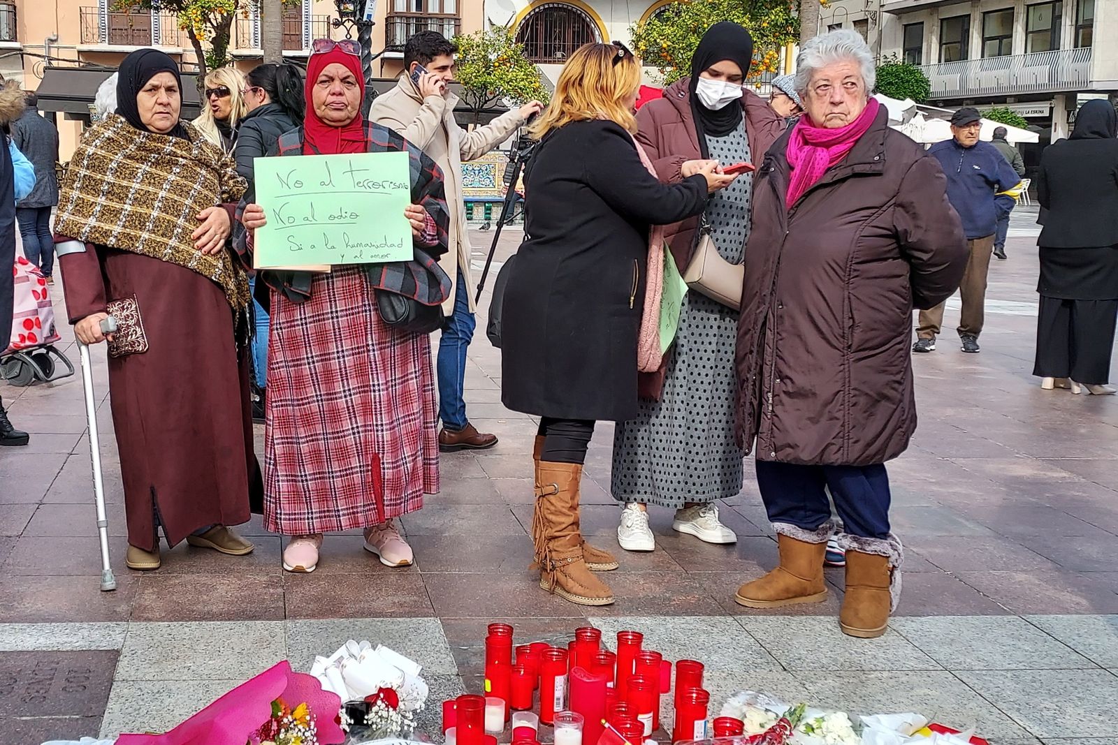 Una mujer sostiene una cartulina con un lema: "No al terrorismo, no al odio, sí a la hermandad y el amor", en el sitio donde Yassine Kanjaa asesinó a Diego Valencia.