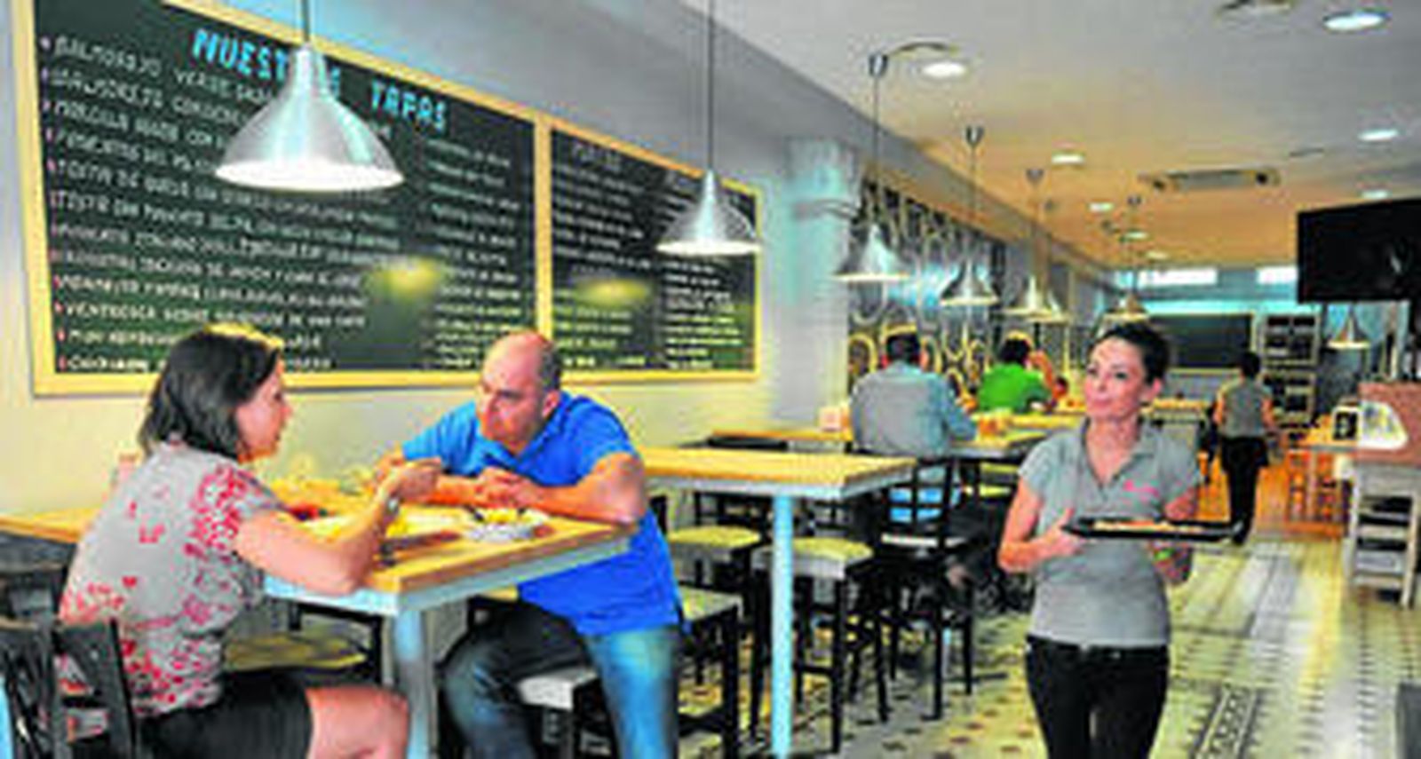 La zona de mesas altas de Tomaré Tapas, que tiene su carta de tapas en las pizarras de la pared.