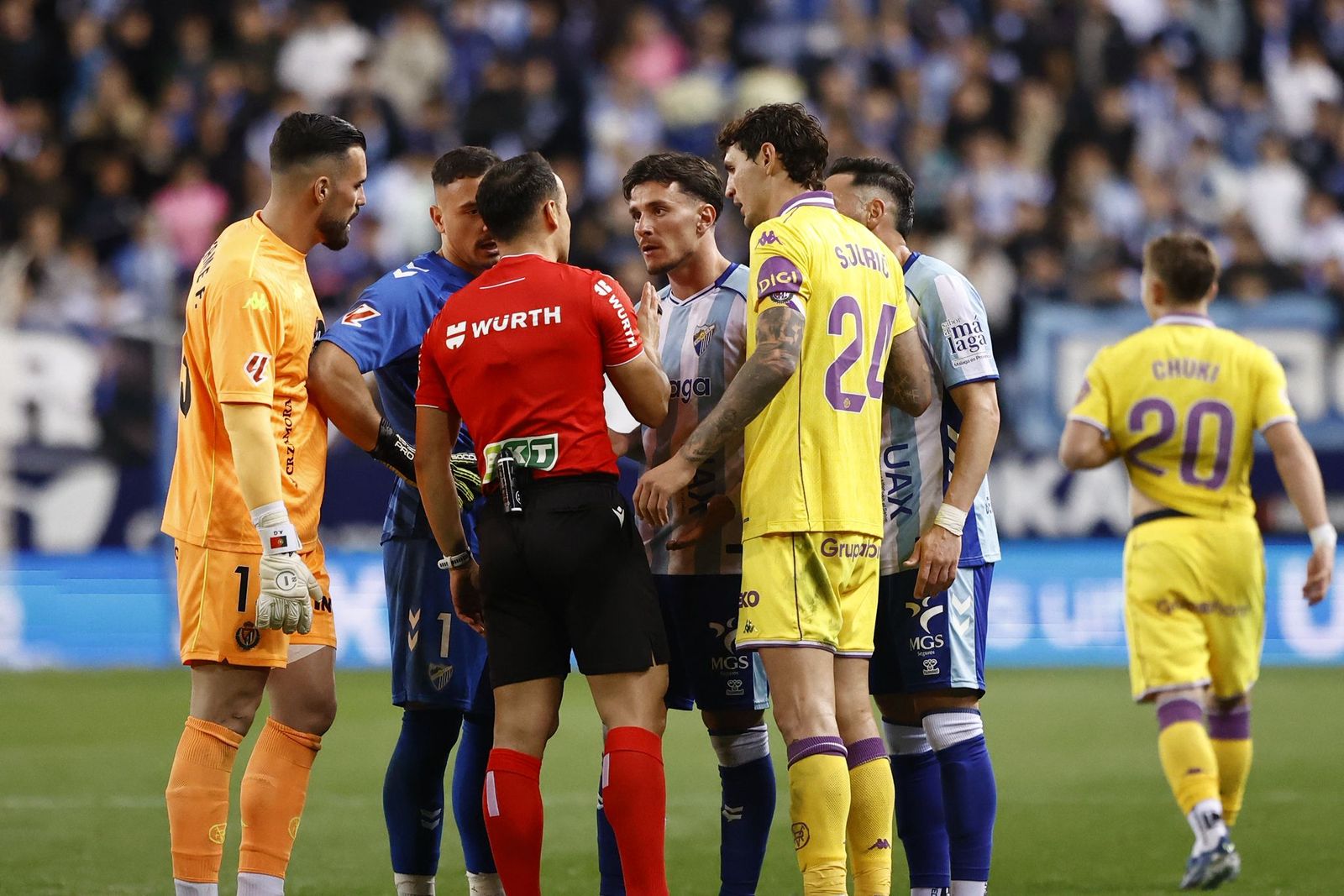 Los jugadores escuchan al árbitro en el Málaga CF-Real Valladolid, en fotos