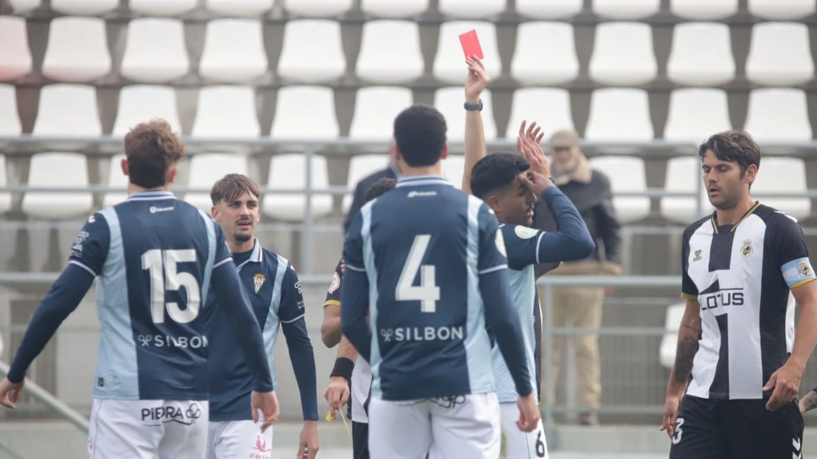 El arbitro sevillano José Miguel Catalán expulsa al visitante Arévalo en medio de una nube de futbolistas