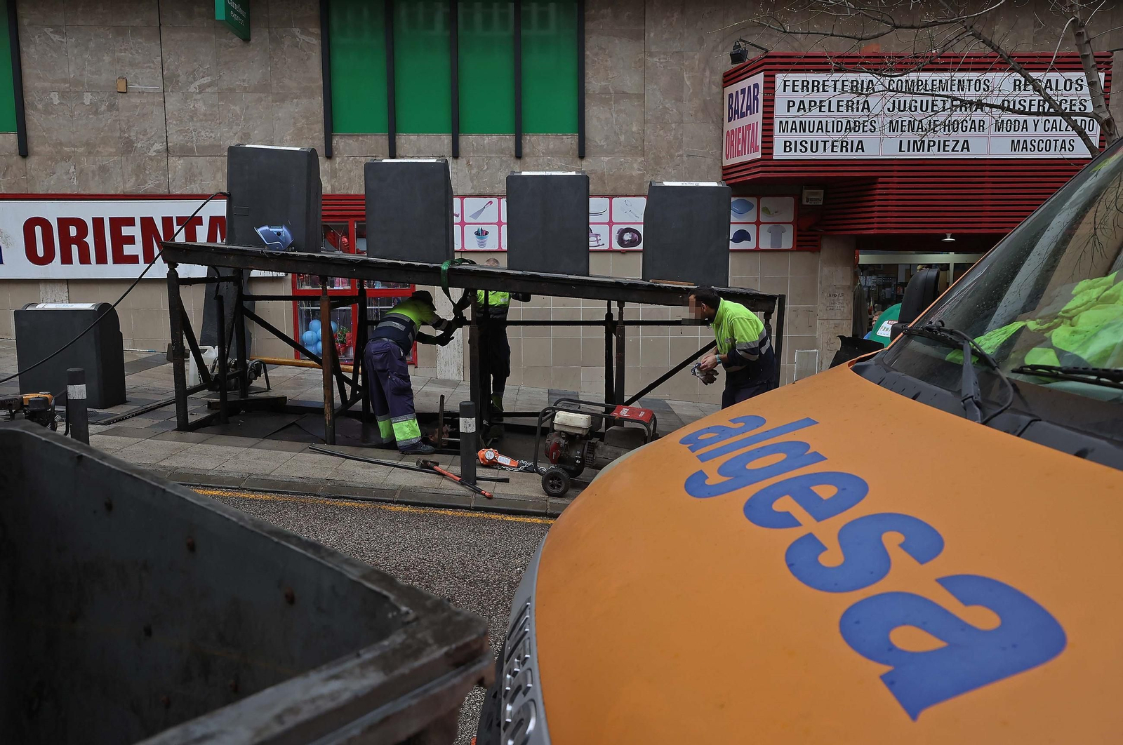 Trabajadores de Algesa reparan la plataforma de unos contenedores soterrados en la calle Trafalgar.