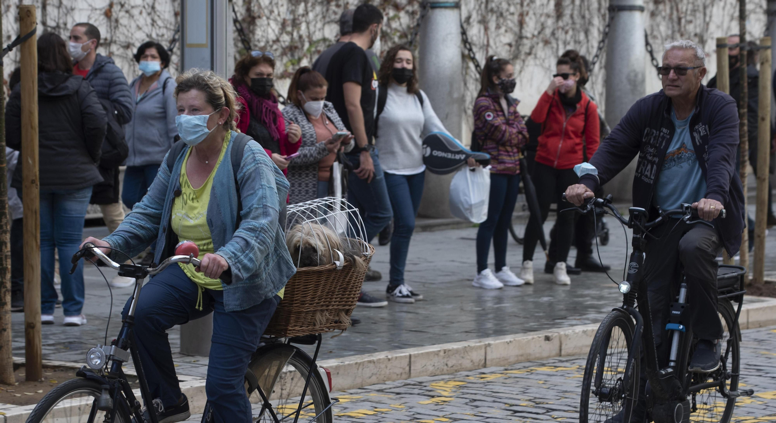 Dos personas circulan en bicicleta con sus mascarillas.