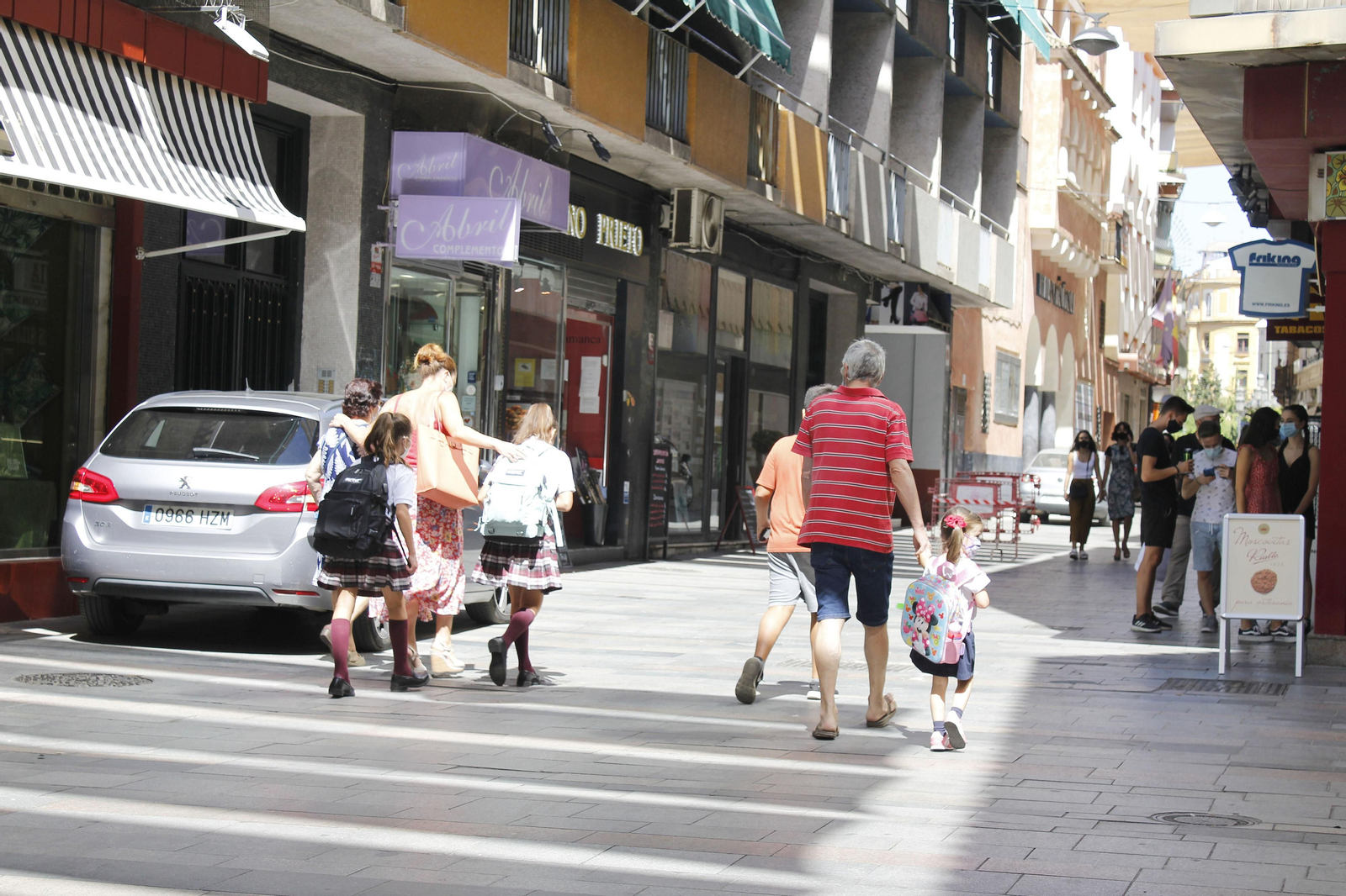 Padres y abuelos caminan con los niños por las calles del centro en la vuelta al cole de 2020.