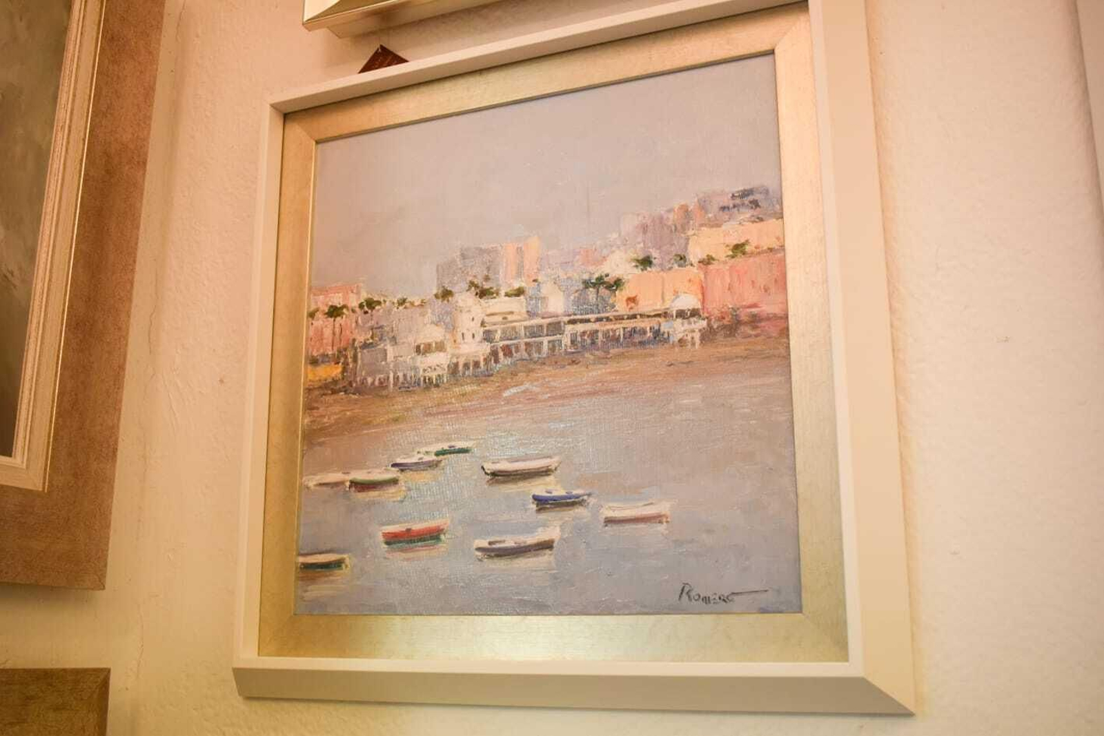 La playa de La Caleta. El Balneario de la Palma y del Real la da una impronta muy diferente a la playa de La Caleta, templo de los viñeros y del casco antiguo de la ciudad. Romero representa esta estampa a espátula. El cuadro cuenta con un marco doble blanco y plata, y un tamaño de 55x55. Su precio es de 335 euros.