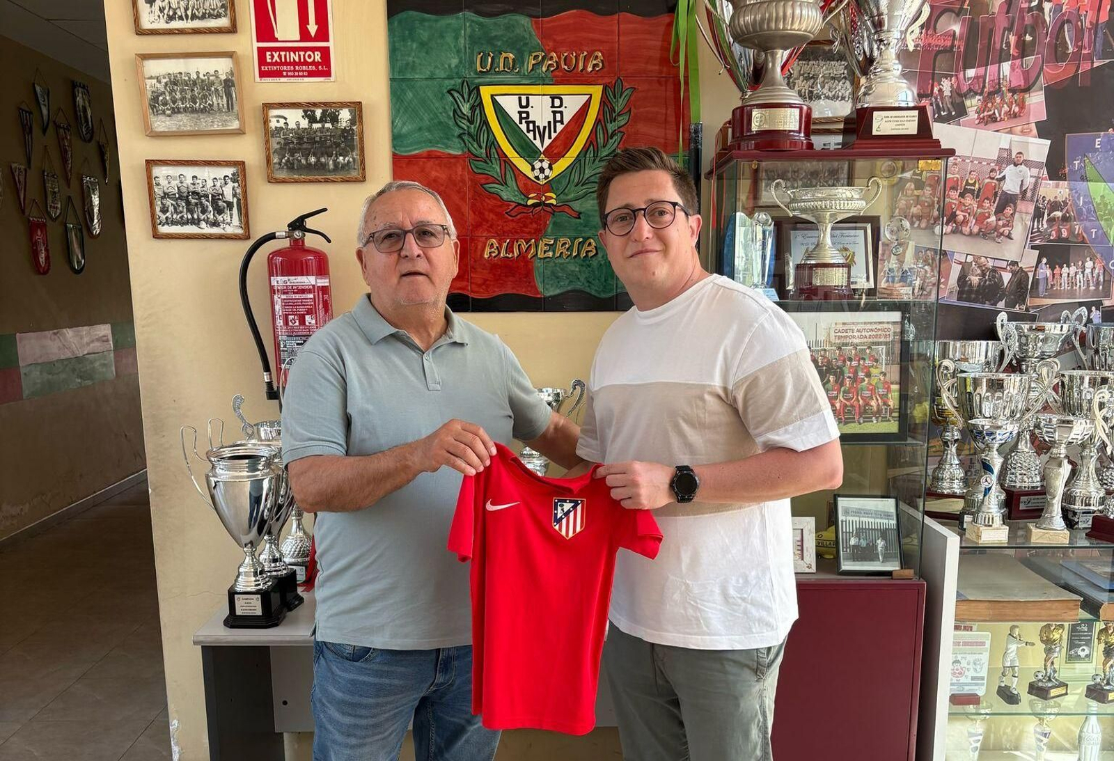 Miembros del club arlequinado posan con una camiseta de entrenamiento del Atlético de Madrid.