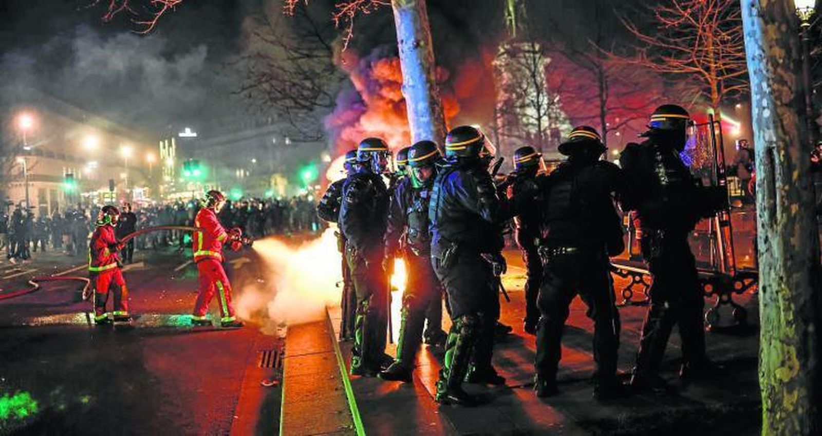 Bomberos apagan un fuego durante las protestas en París contra la reforma de las pensiones.