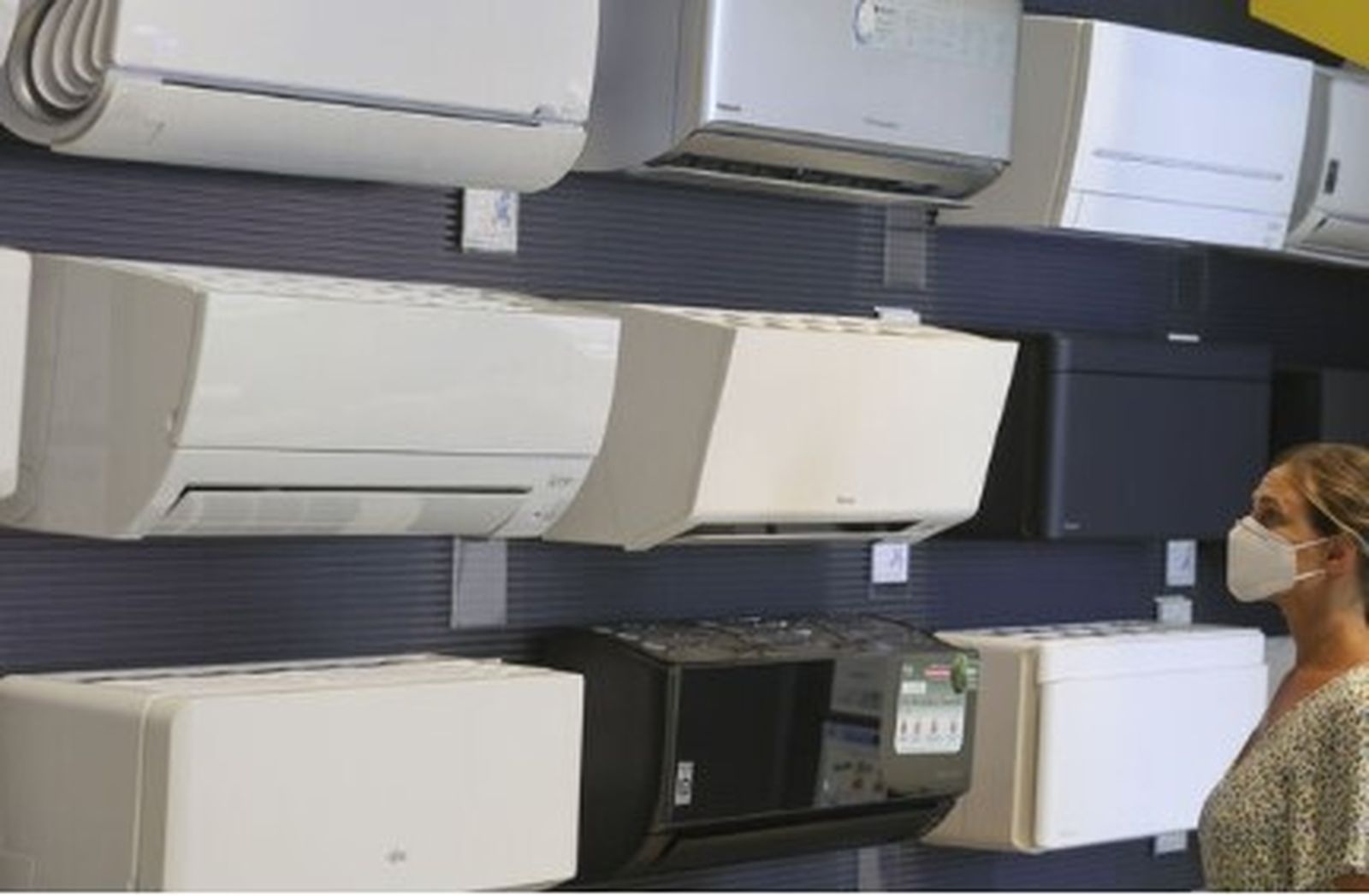 Una mujer mira los apartados de aire acondicionado disponibles en una tienda de electrodomésticos